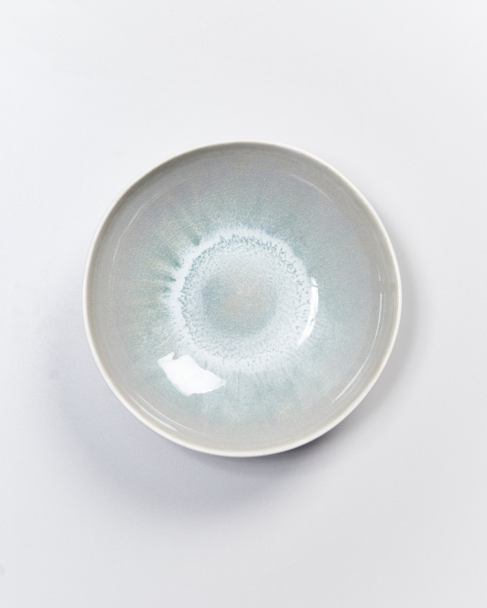 Keramikschale mit blaugrauer Glasur und kreisförmigem Muster, auf hellem Hintergrund fotografiert.