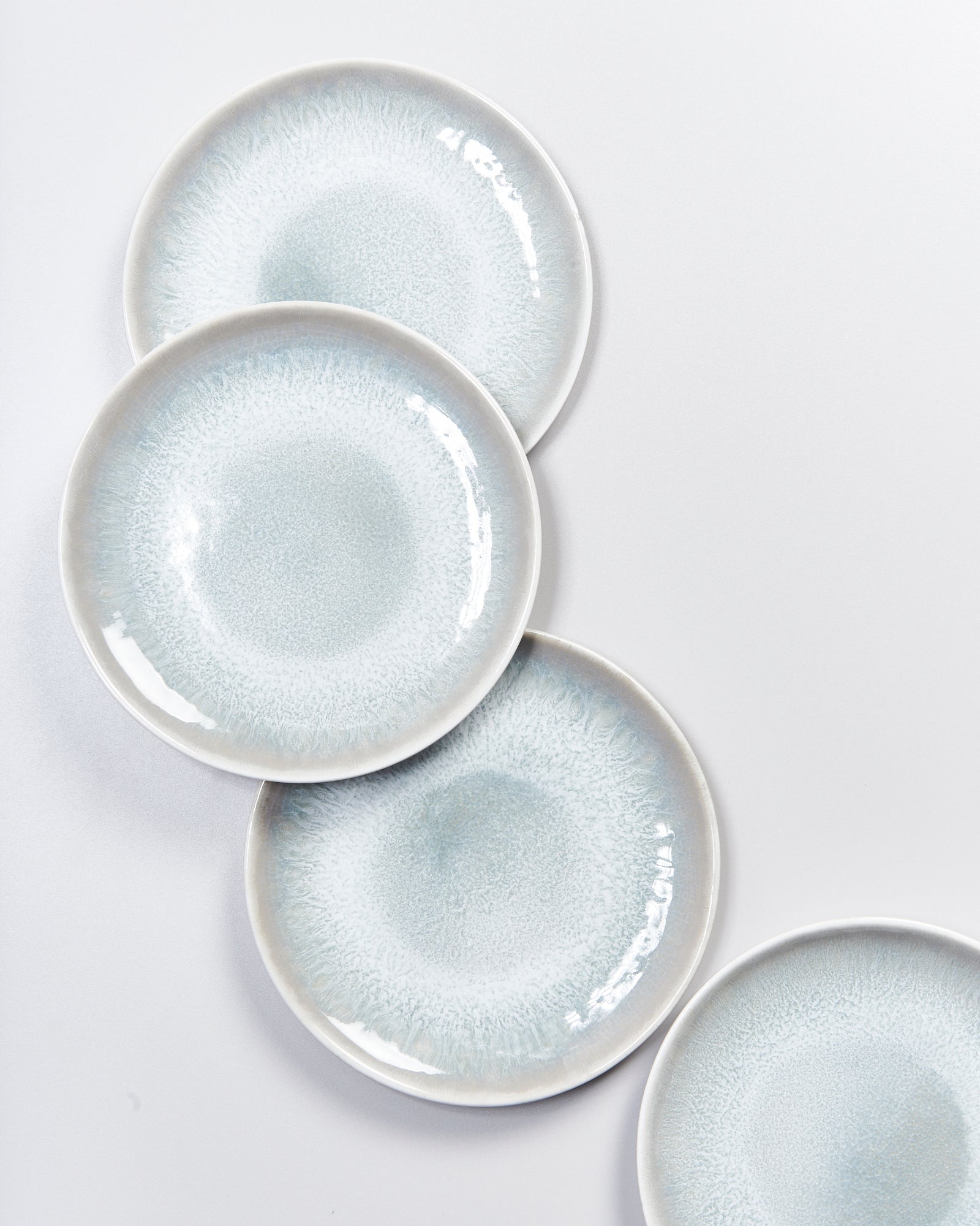 Vier blaue, strukturierte Keramikteller überlappen sich auf einem weißen Hintergrund.