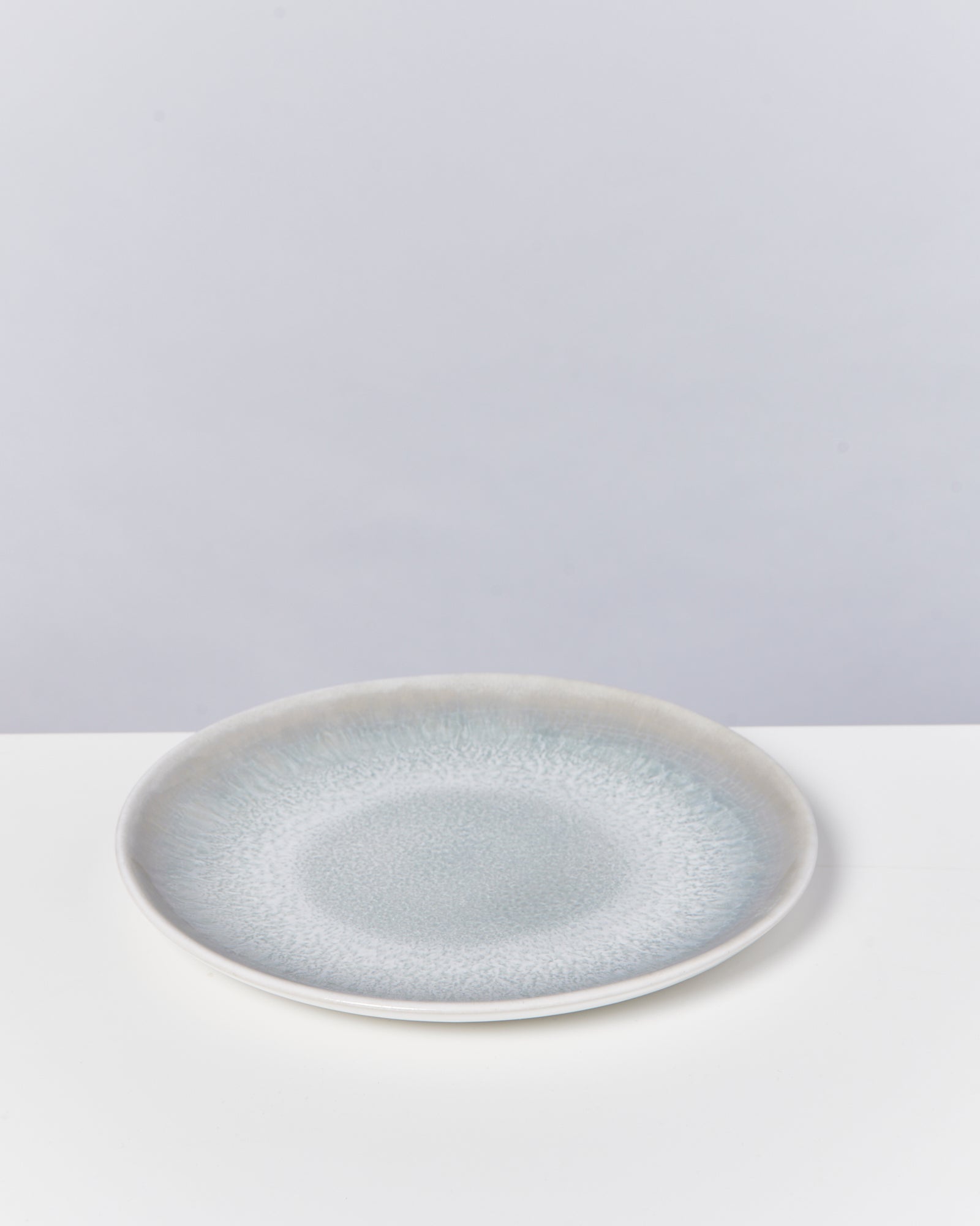 Grauer Keramikteller mit texturierter Oberfläche auf weißem Hintergrund.