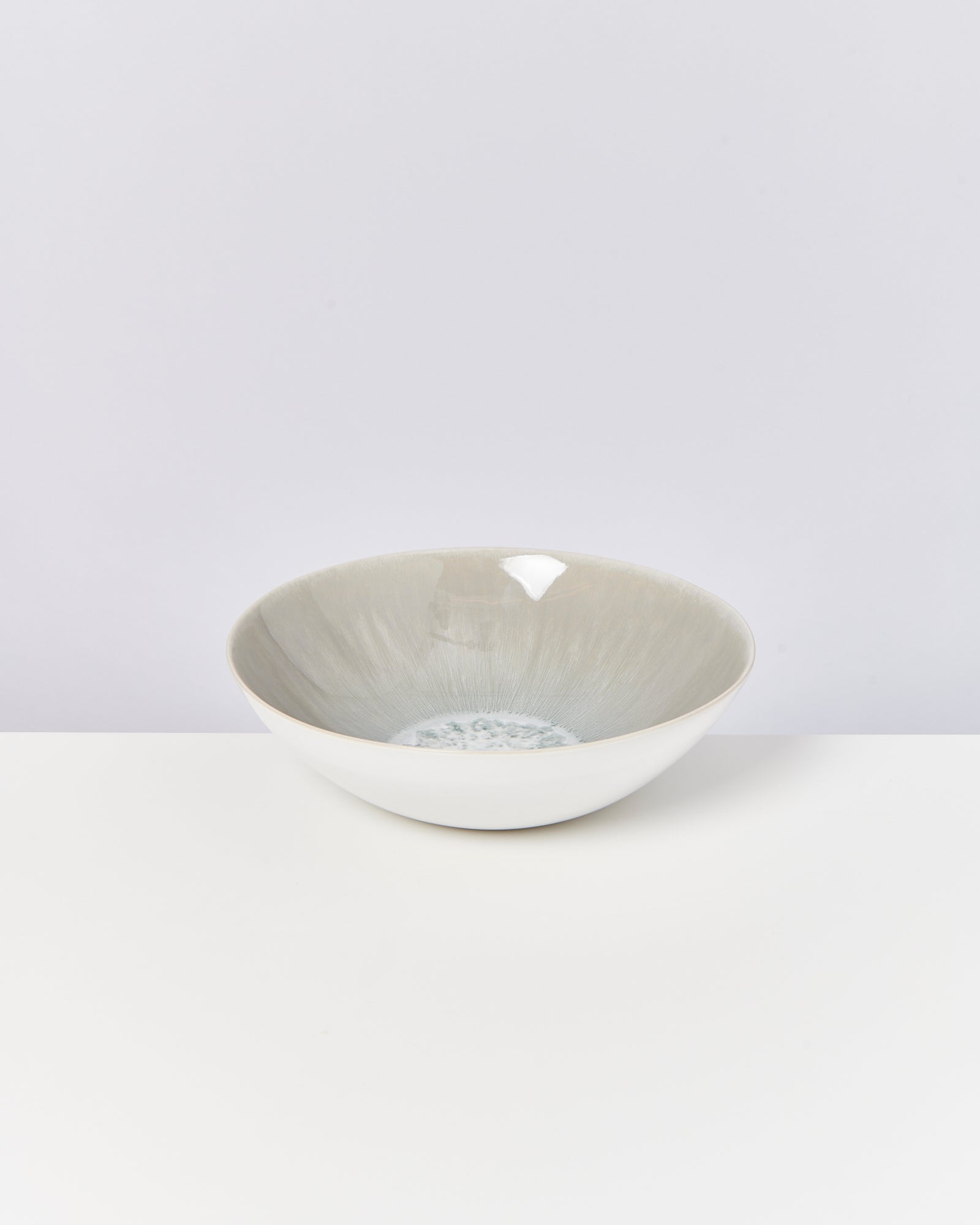 Weiße, runde Schale mit grauen und blauen Details im Inneren auf einem weißen Hintergrund platziert.