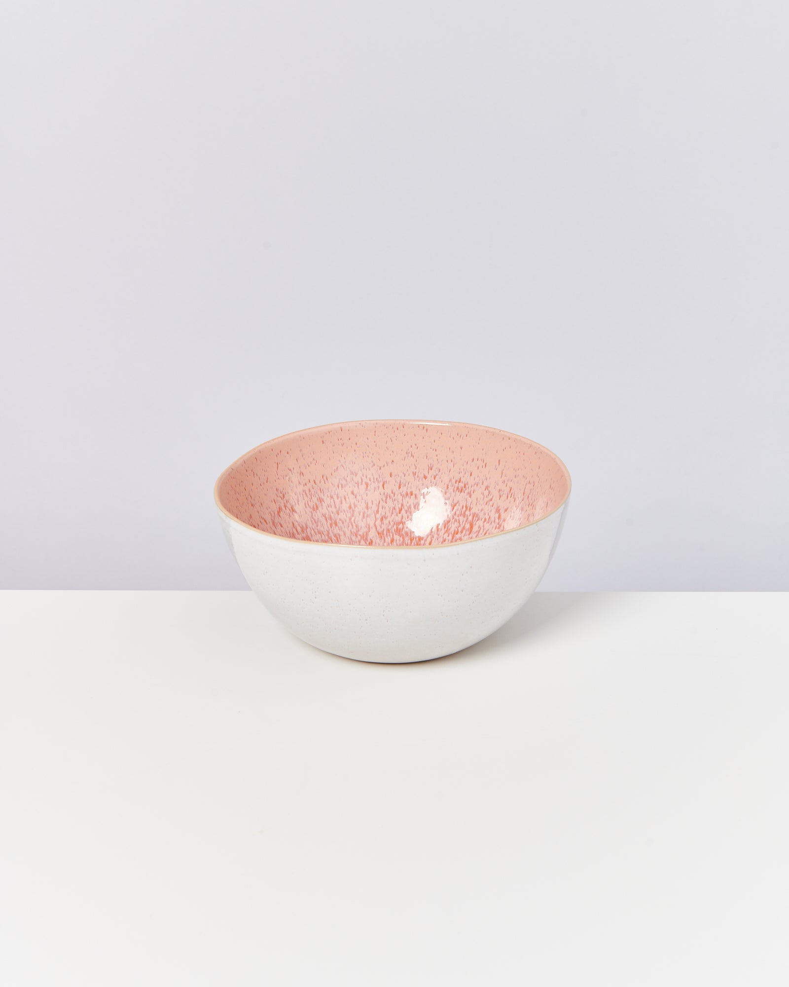 Weiße Schüssel mit rosa gesprenkeltem Inneren auf weißem Hintergrund.