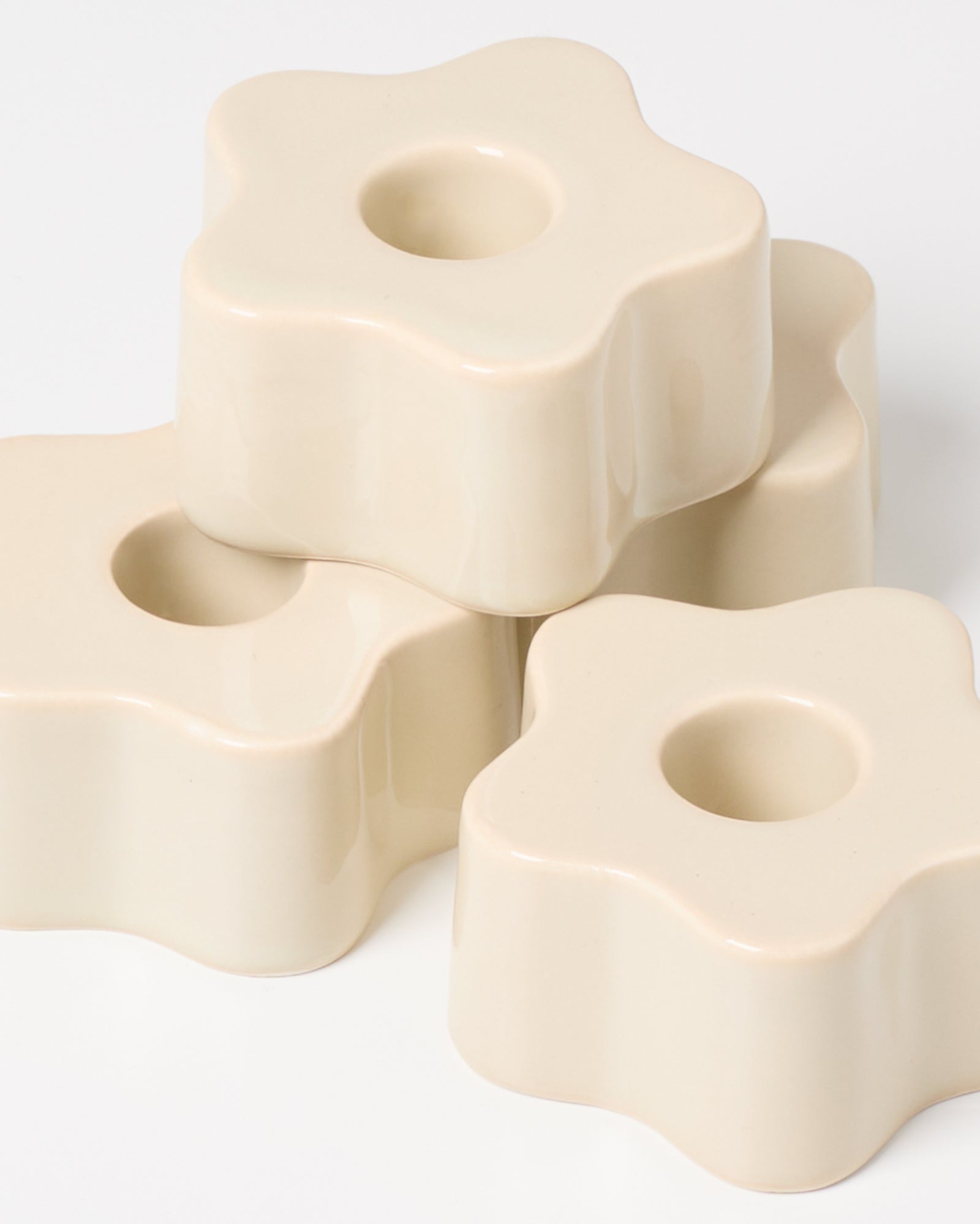 Beige, blumenförmige Keramikobjekte mit zentralen Vertiefungen, auf einem weißen Hintergrund gestapelt.