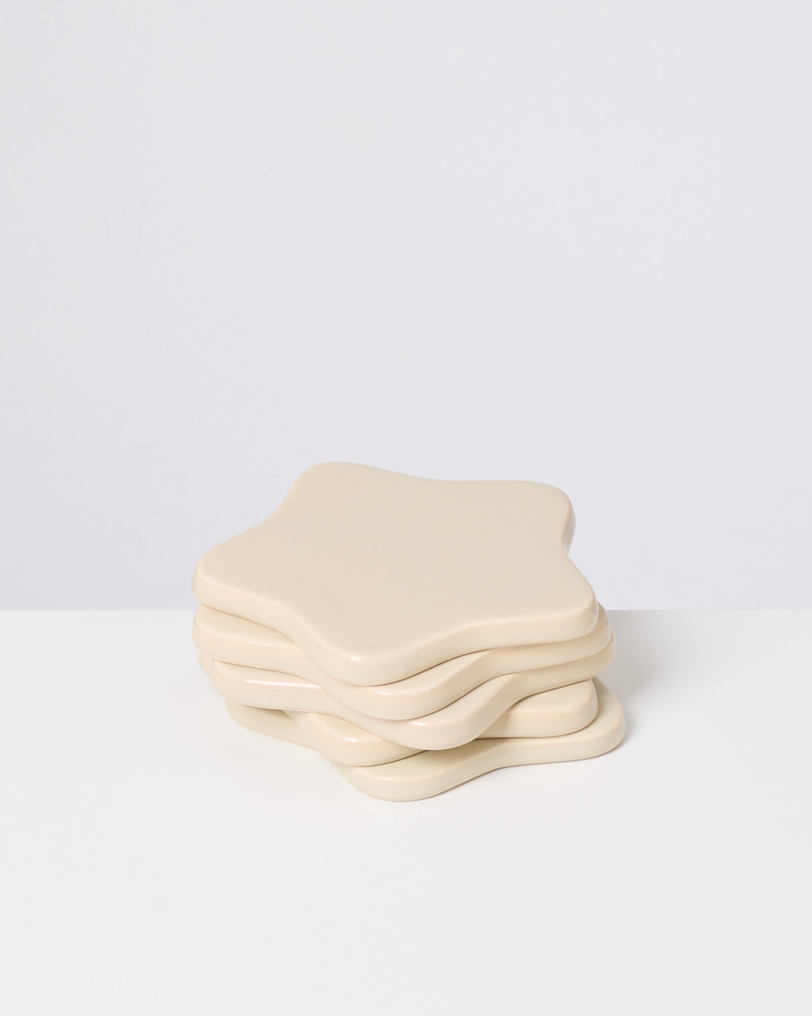 Beige, sternförmige Untersetzer auf einem weißen Hintergrund gestapelt.