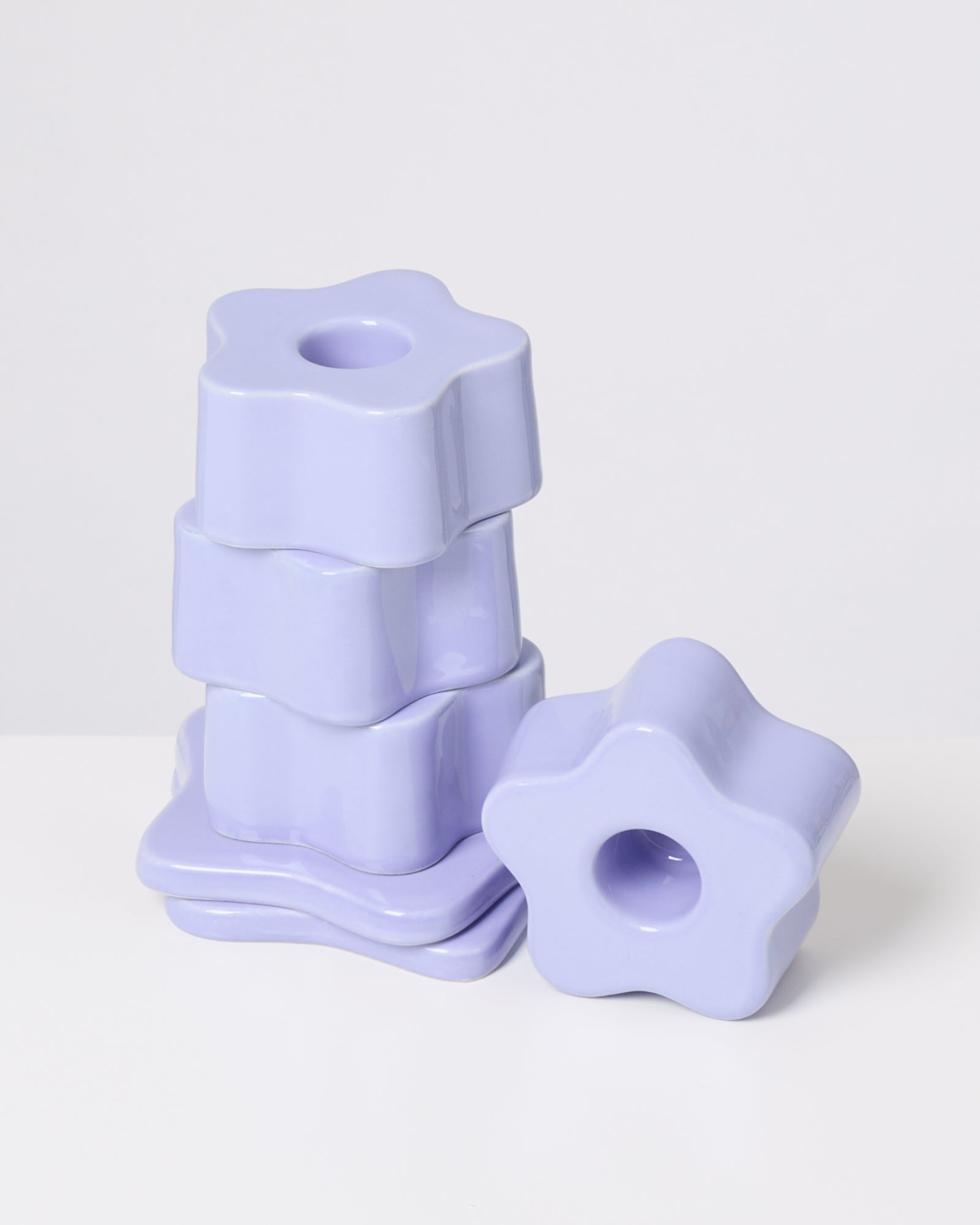 Lila, sternförmige Stapelsteine aus Keramik auf weißem Hintergrund, eine liegt separat.