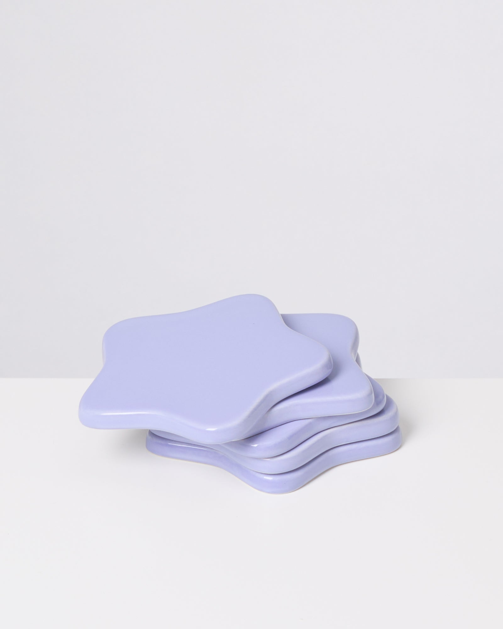 Vier lilafarbene, sternförmige Untersetzer auf einem weißen Hintergrund.