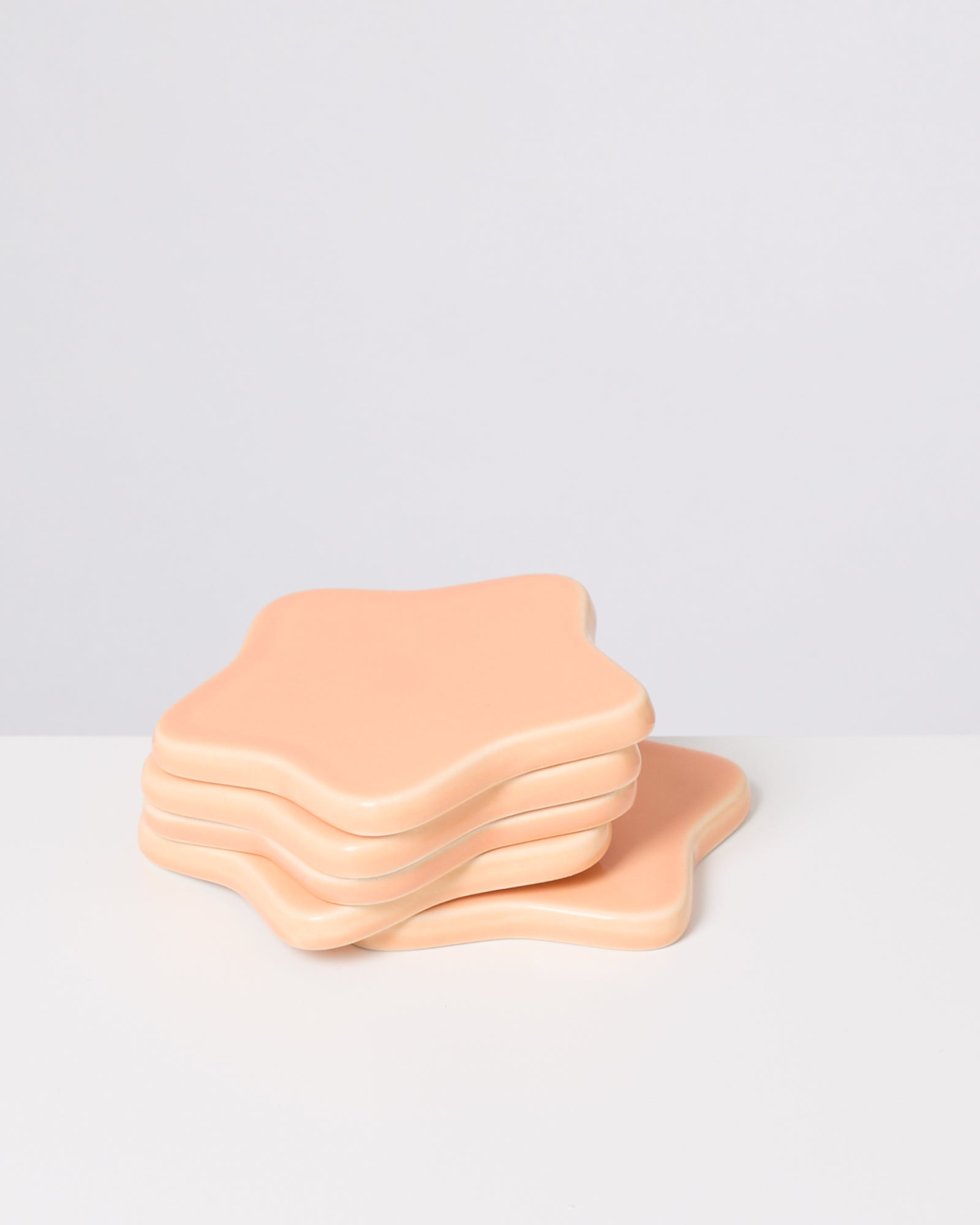 Vier beige, sternförmige Untersetzer stapeln sich auf einem weißen Hintergrund.