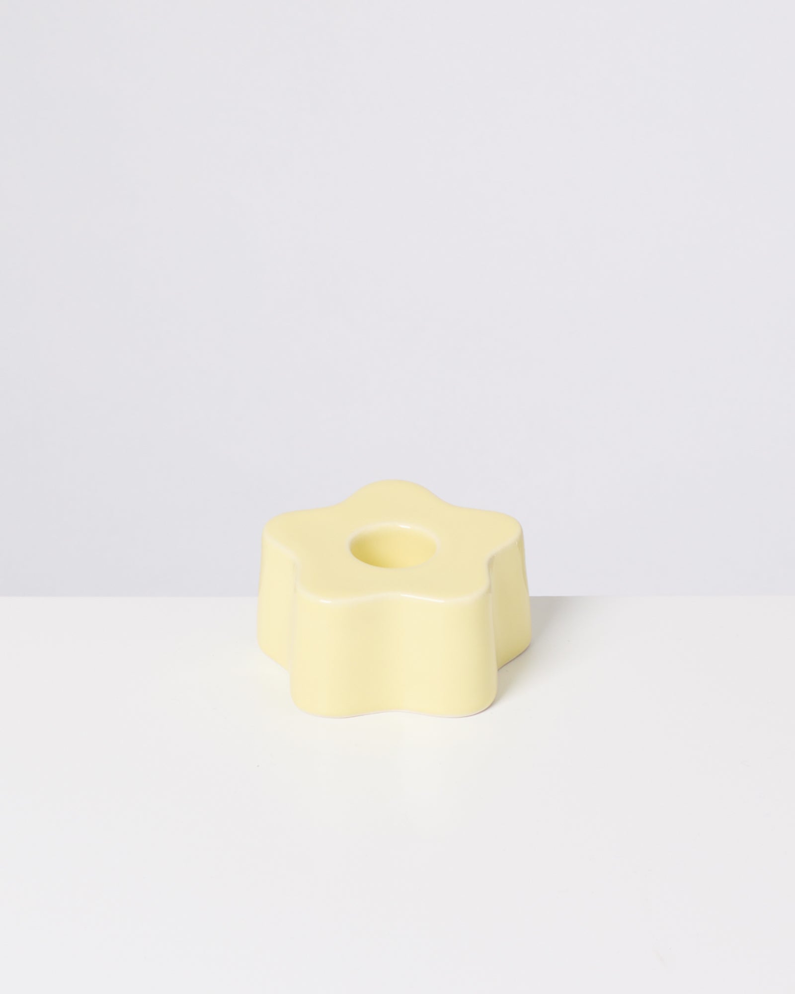 Gelbes, sternförmiges Objekt mit Loch in der Mitte auf weißem Hintergrund.