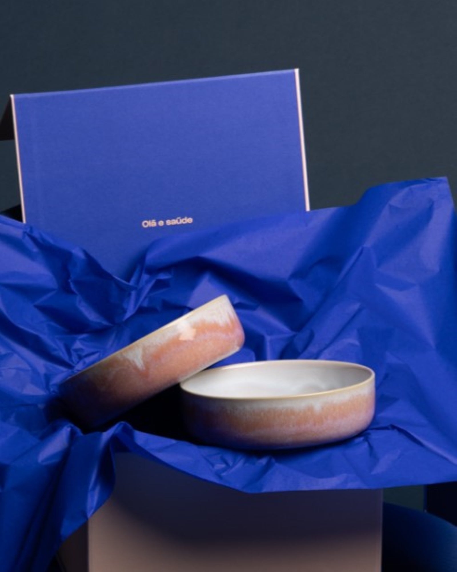 Zwei Keramikschalen auf blauem Seidenpapier vor einer blauen Schachtel.
