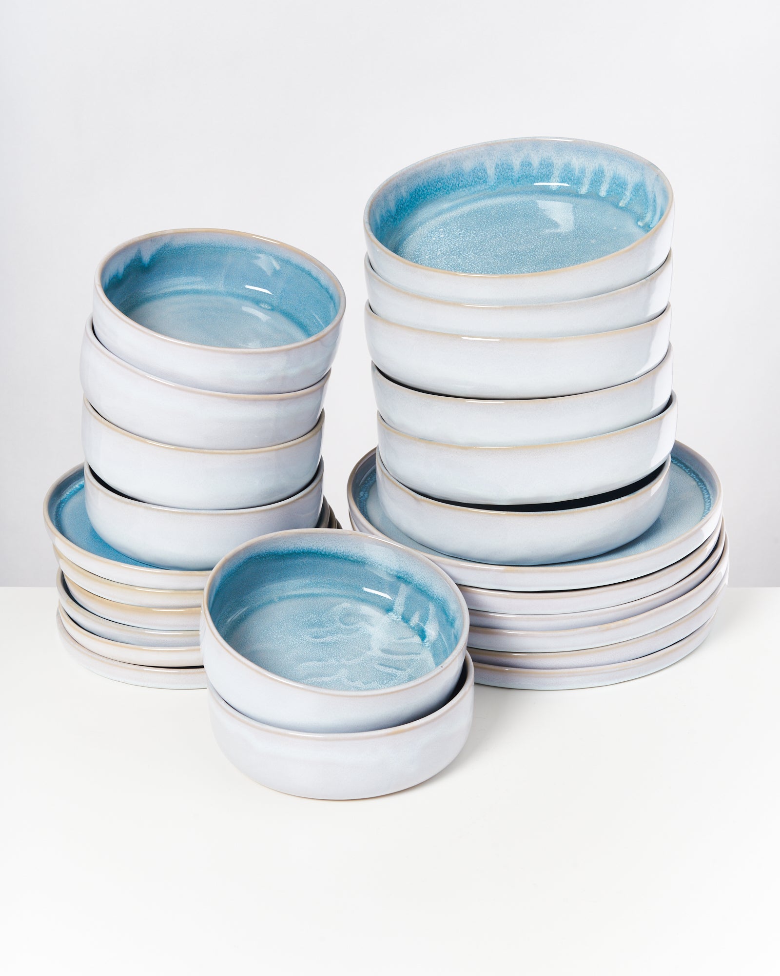 Stapel von weiß-blauen Keramikschalen mit glänzender Oberfläche auf einem weißen Hintergrund.