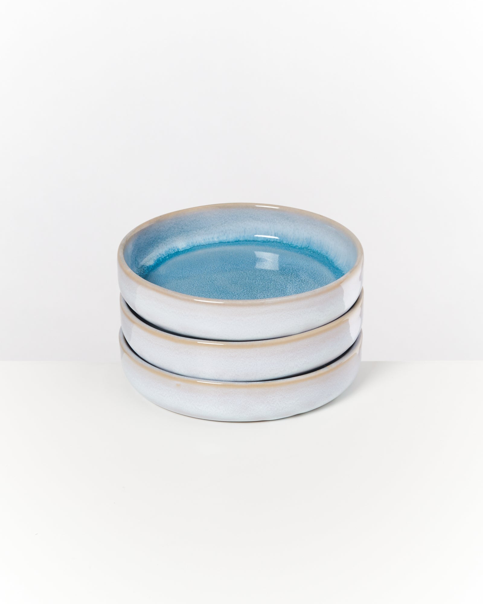 Drei gestapelte Teller mit grauer Außenseite und blauem Inneren auf weißem Hintergrund.