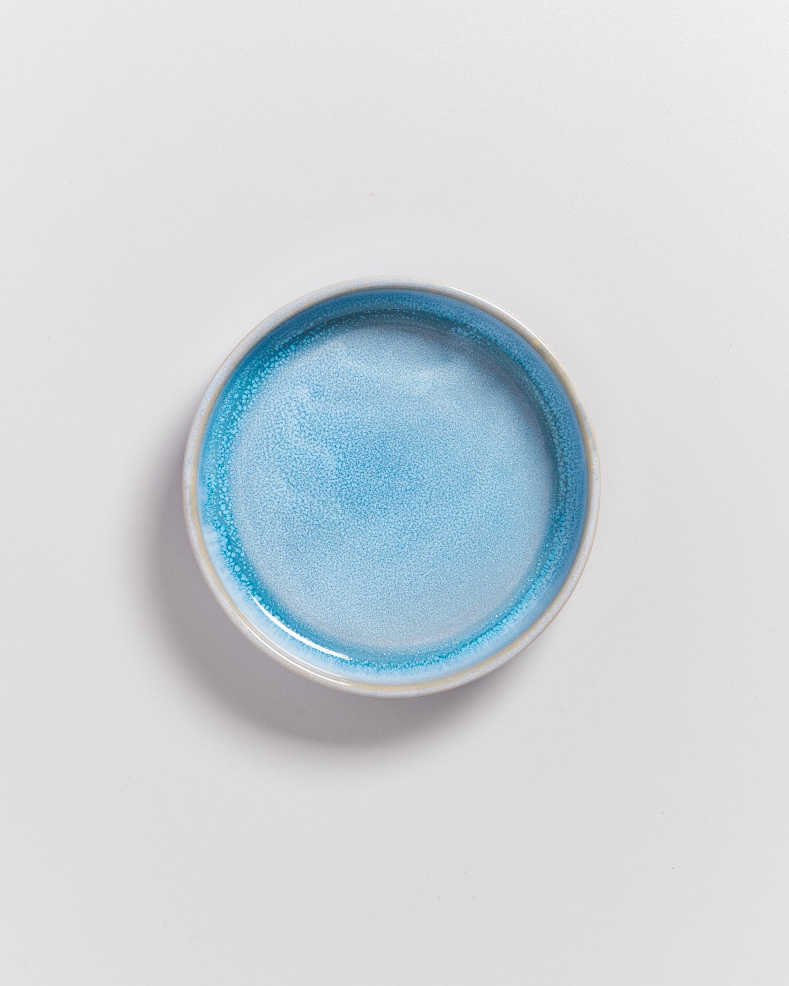 Keramikteller mit hellblauer Glasur auf weißem Hintergrund.