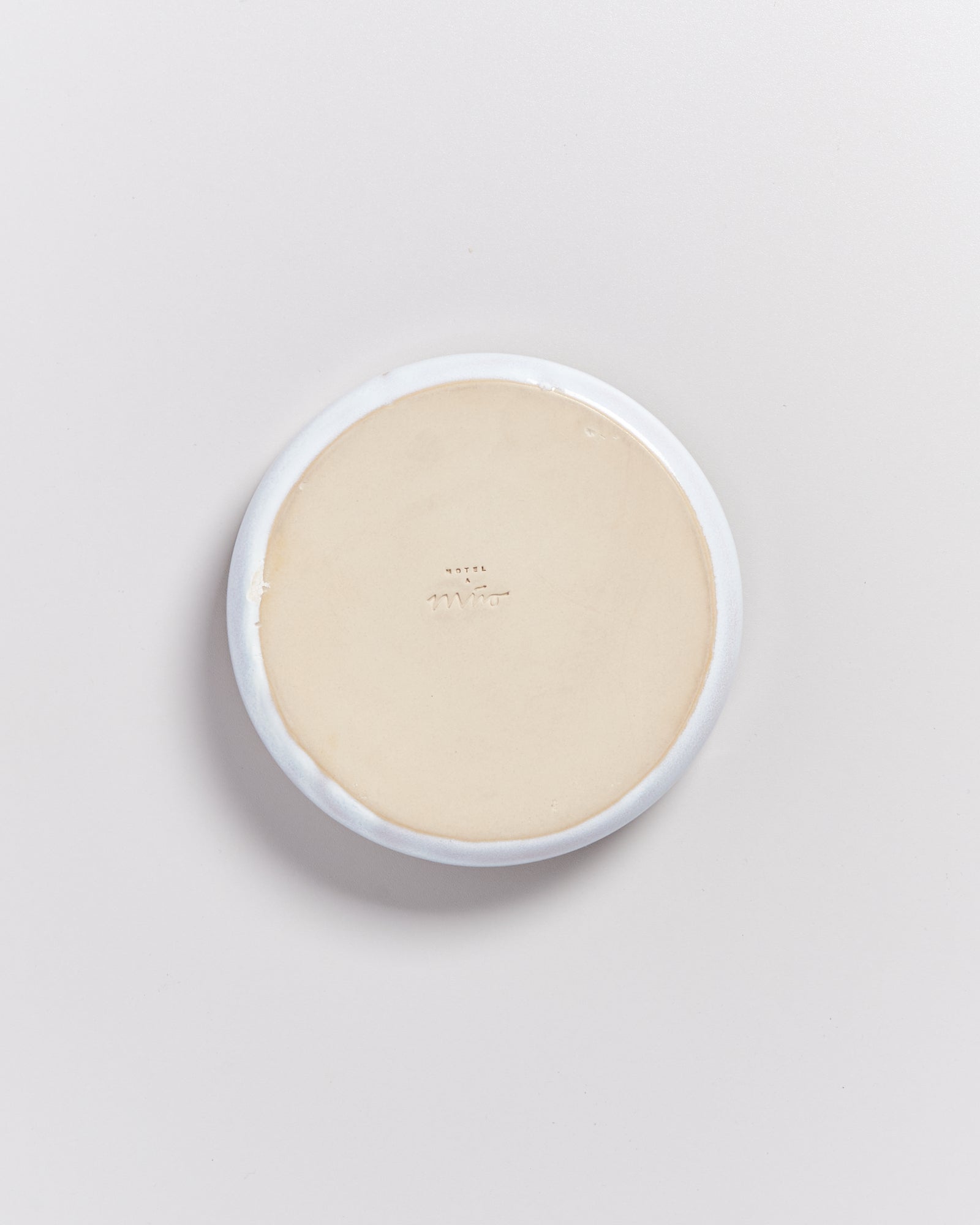 Eine runde Seife mit weißem Rand liegt auf einem hellen Hintergrund.