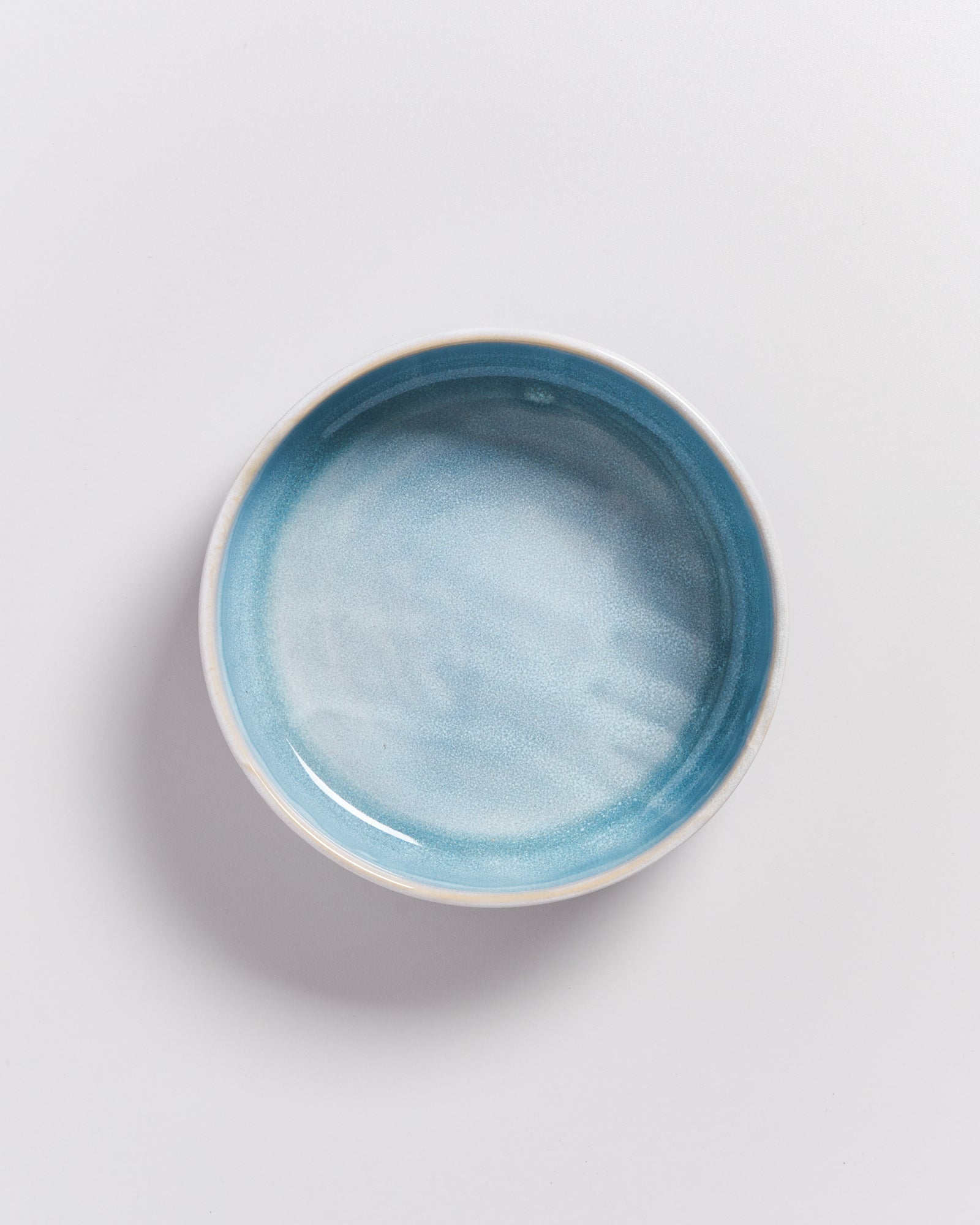 Ein runder, hellblauer Keramikteller auf weißem Hintergrund.