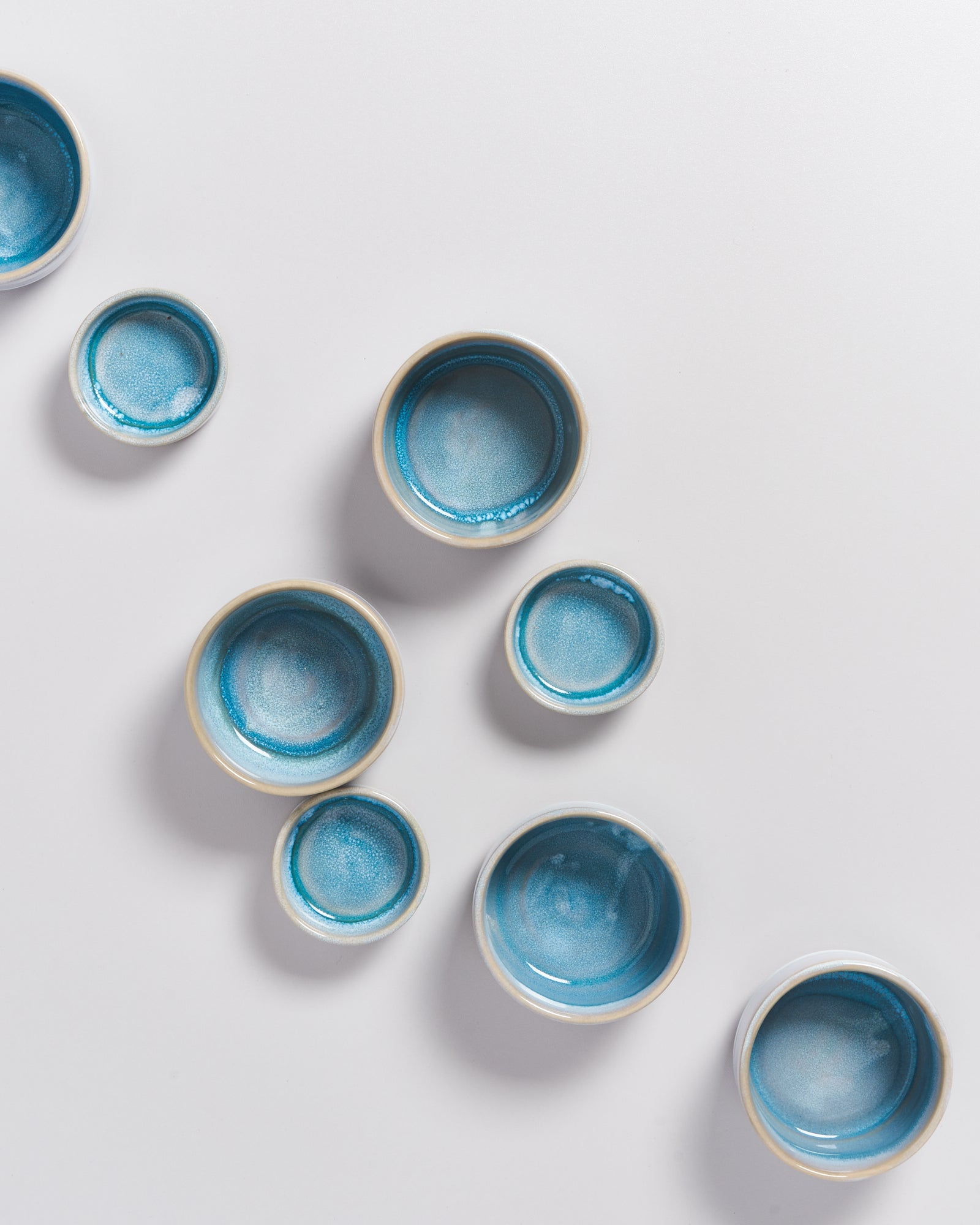 Acht blaue Keramikschalen in verschiedenen Größen auf weißem Hintergrund.