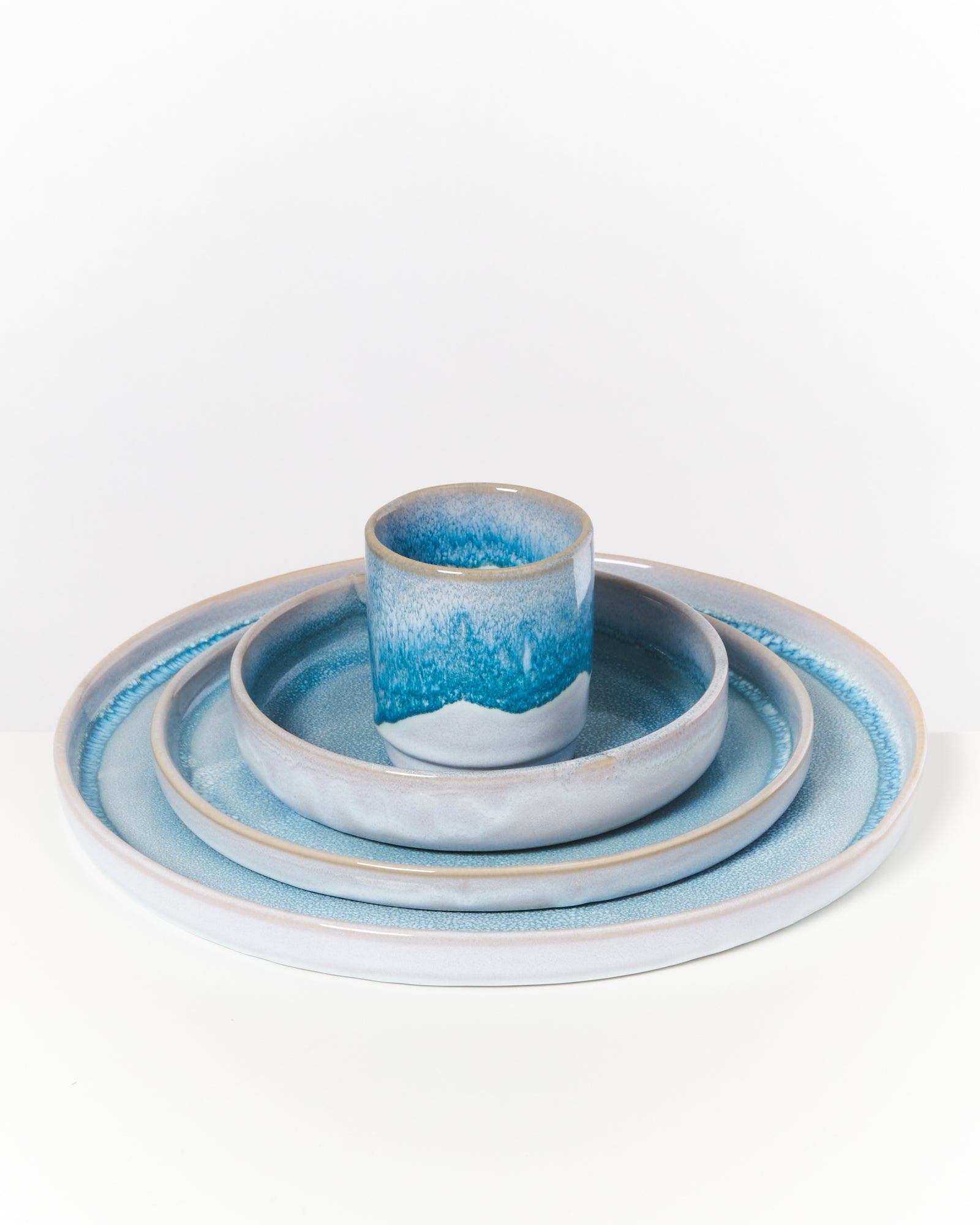 Ein blau-weißes Keramikgeschirrset mit vier Teilen, auf einem weißen Untergrund gestapelt.