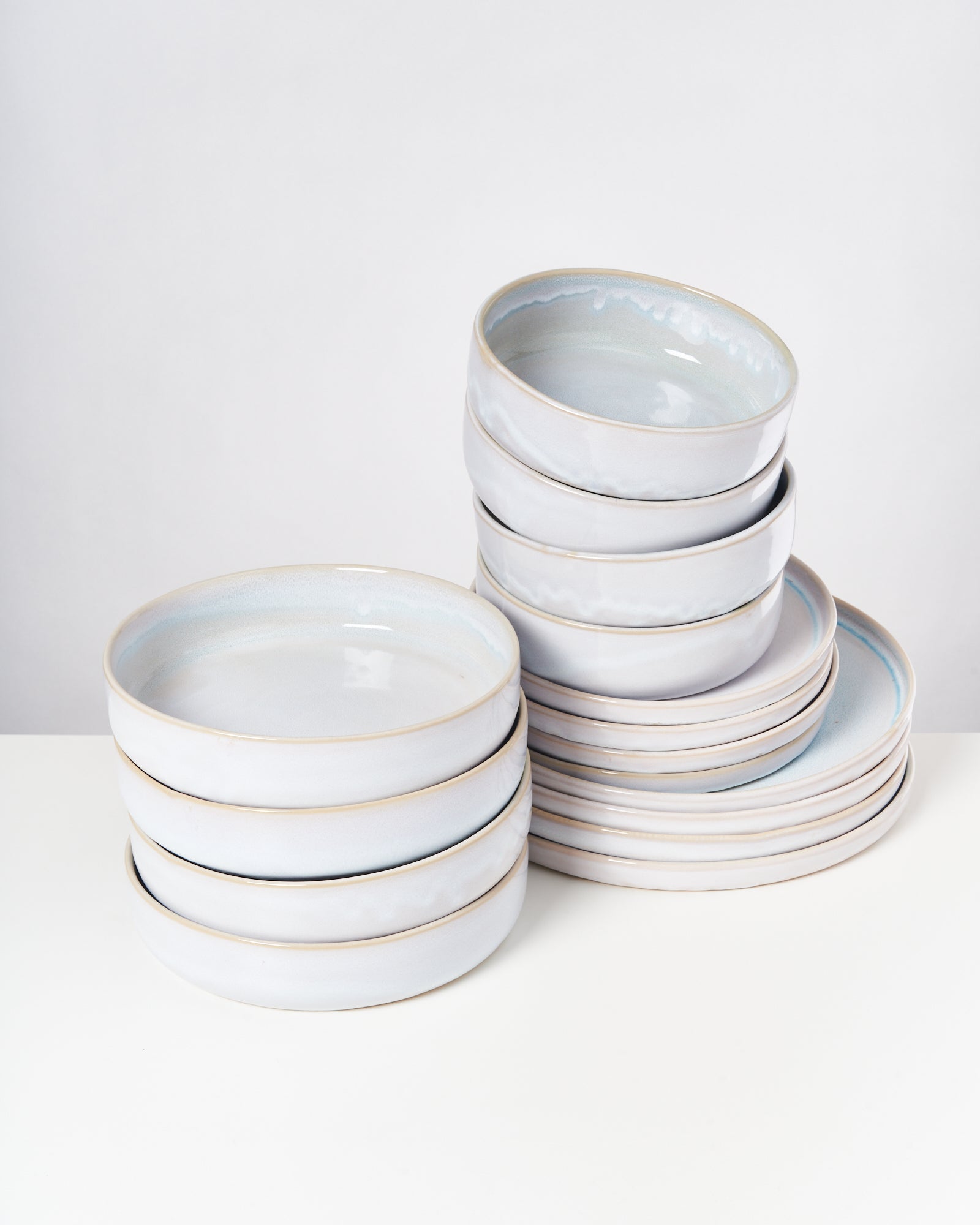 Zwei Stapel aus mehreren weißen Keramikschalen stehen auf einem weißen Untergrund.