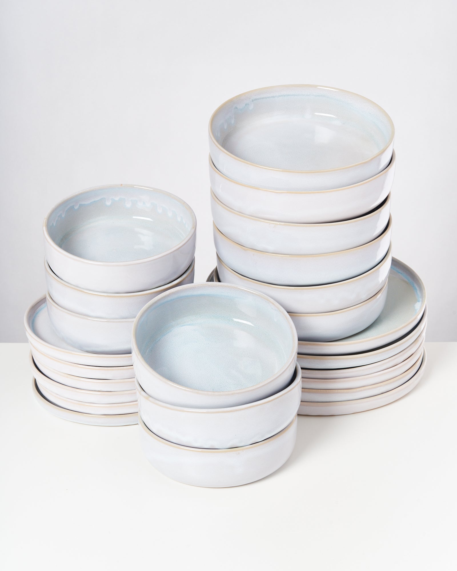 Ein Stapel aus weißen Keramikschalen und -tellern steht auf weißem Hintergrund.