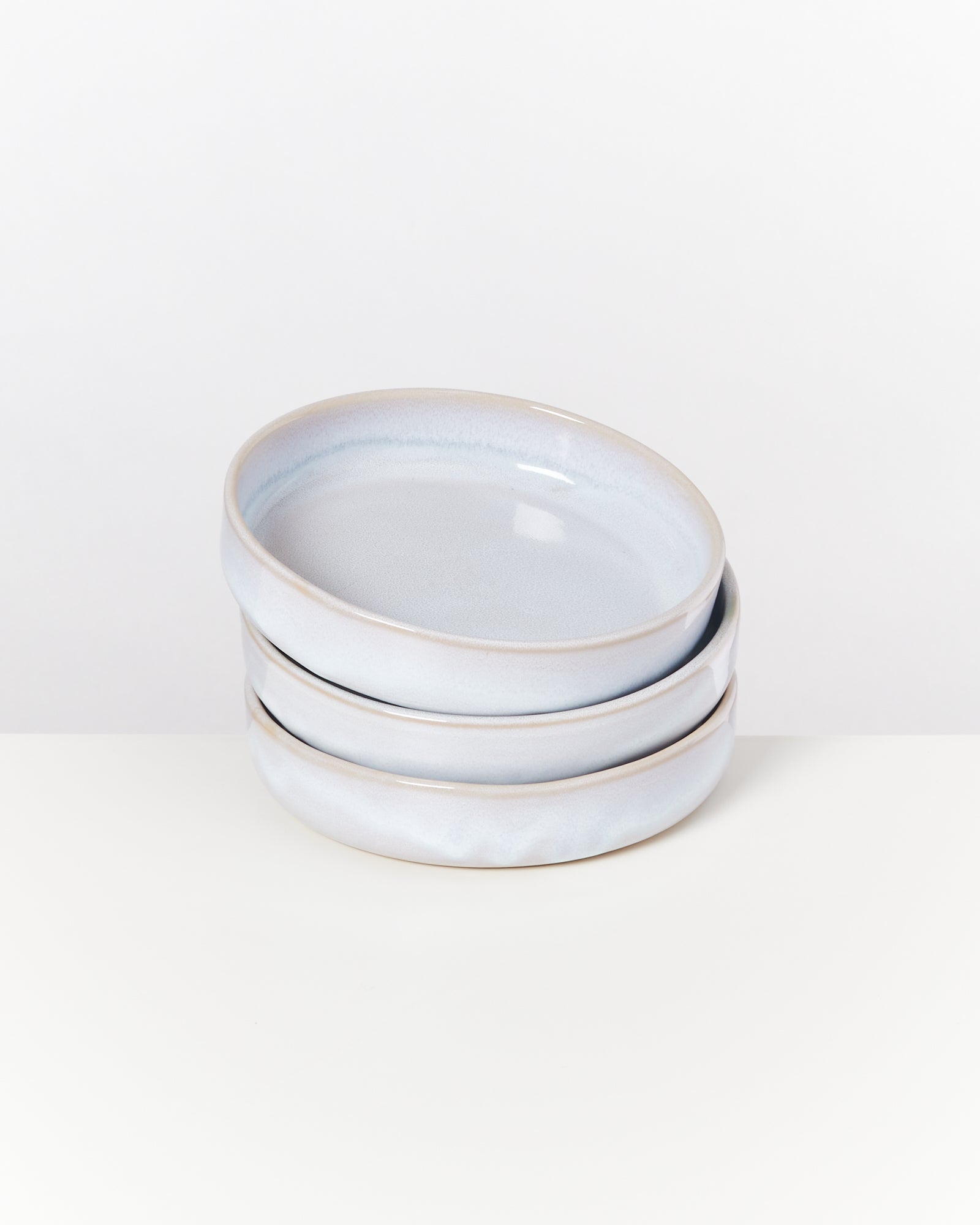 Drei übereinander gestapelte, hellblaue Keramikteller vor einem weißen Hintergrund.