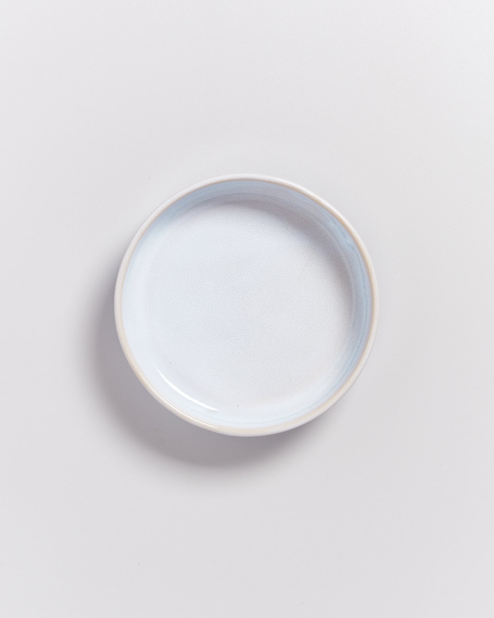 Ein weißer, runder Teller vor einem hellgrauen Hintergrund.