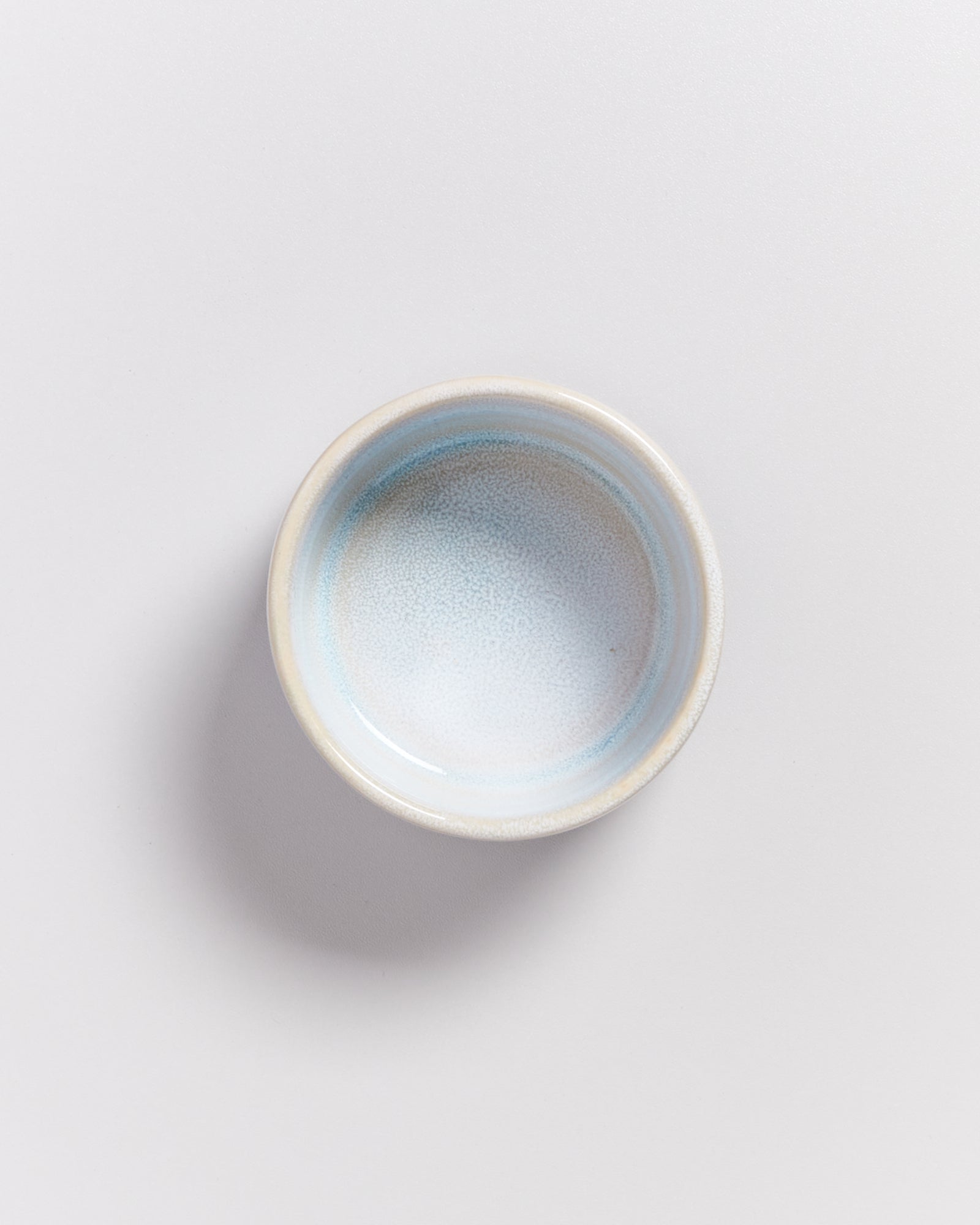 Keramikschale in sanften Blautönen auf neutralem Hintergrund, von oben betrachtet.