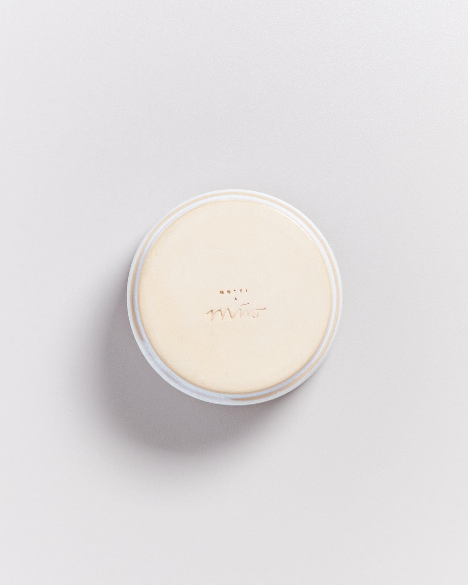 Eine runde, beige Seife mit der Aufschrift "Hotel Miro" auf einem hellen Hintergrund.
