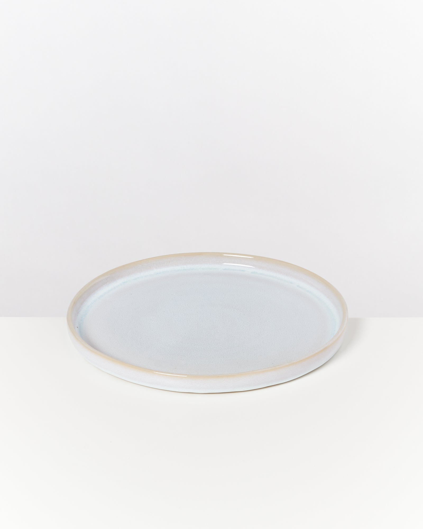 Flacher, hellblauer Keramikteller mit leicht erhobenem Rand auf weißem Hintergrund.