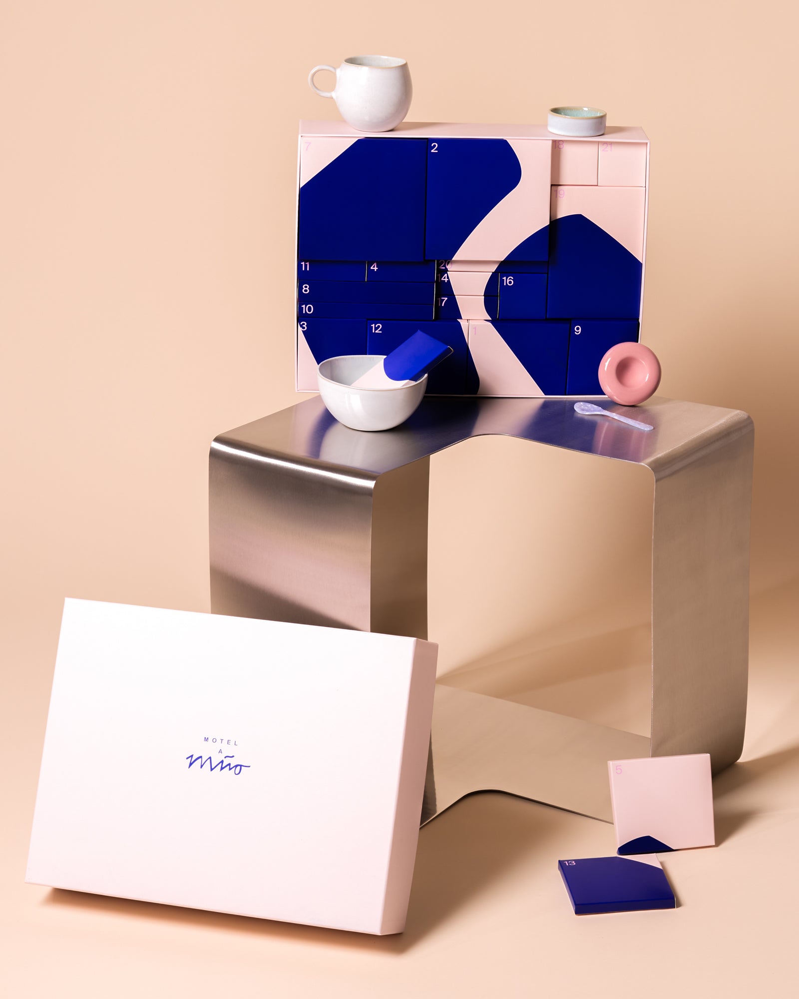 Ein stilvoller Adventskalender mit blauen und rosafarbenen Akzenten auf einem modernen, metallischen Tisch platziert.