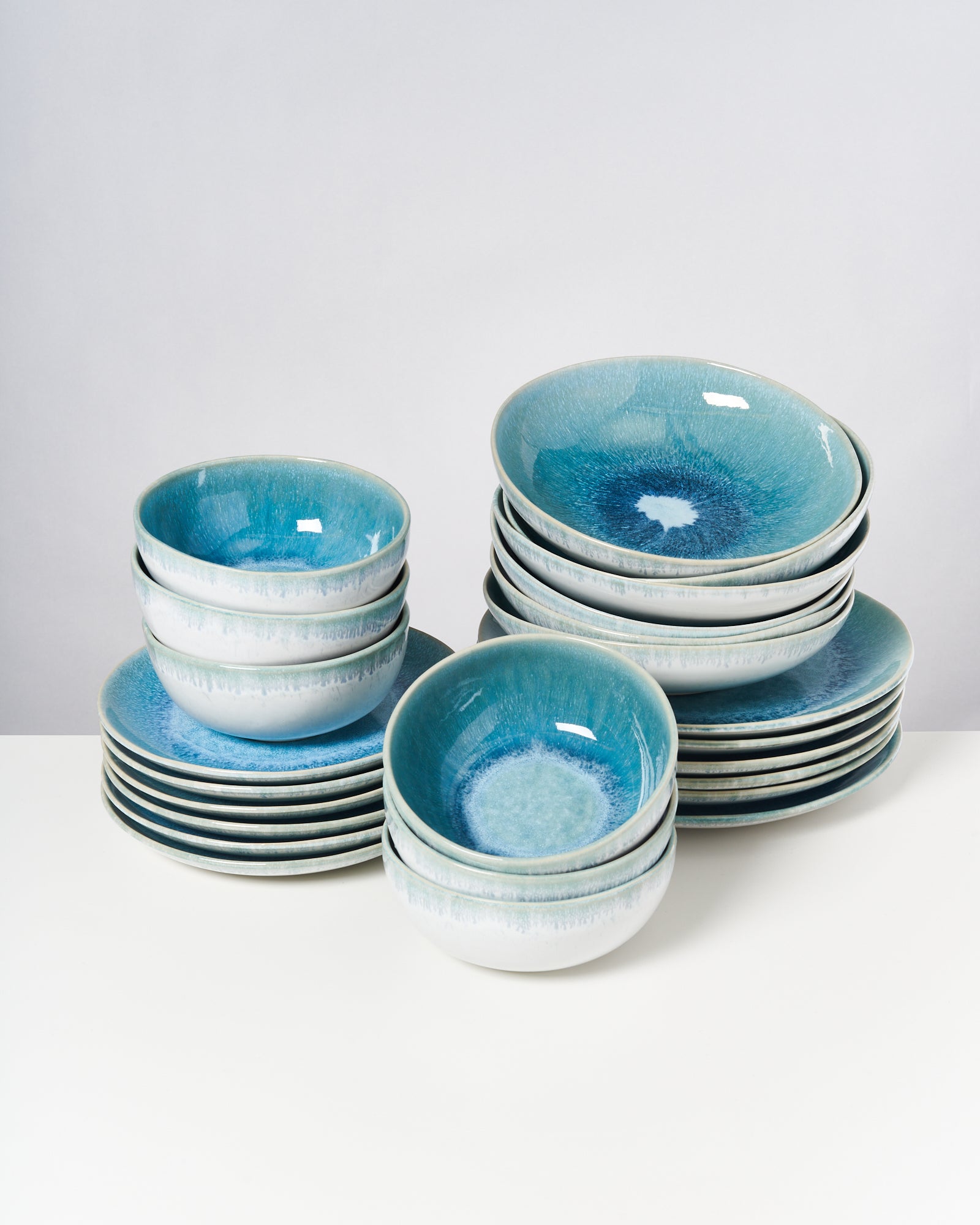 Gestapelte, blaue Keramikteller und -schalen auf einem weißen Untergrund.