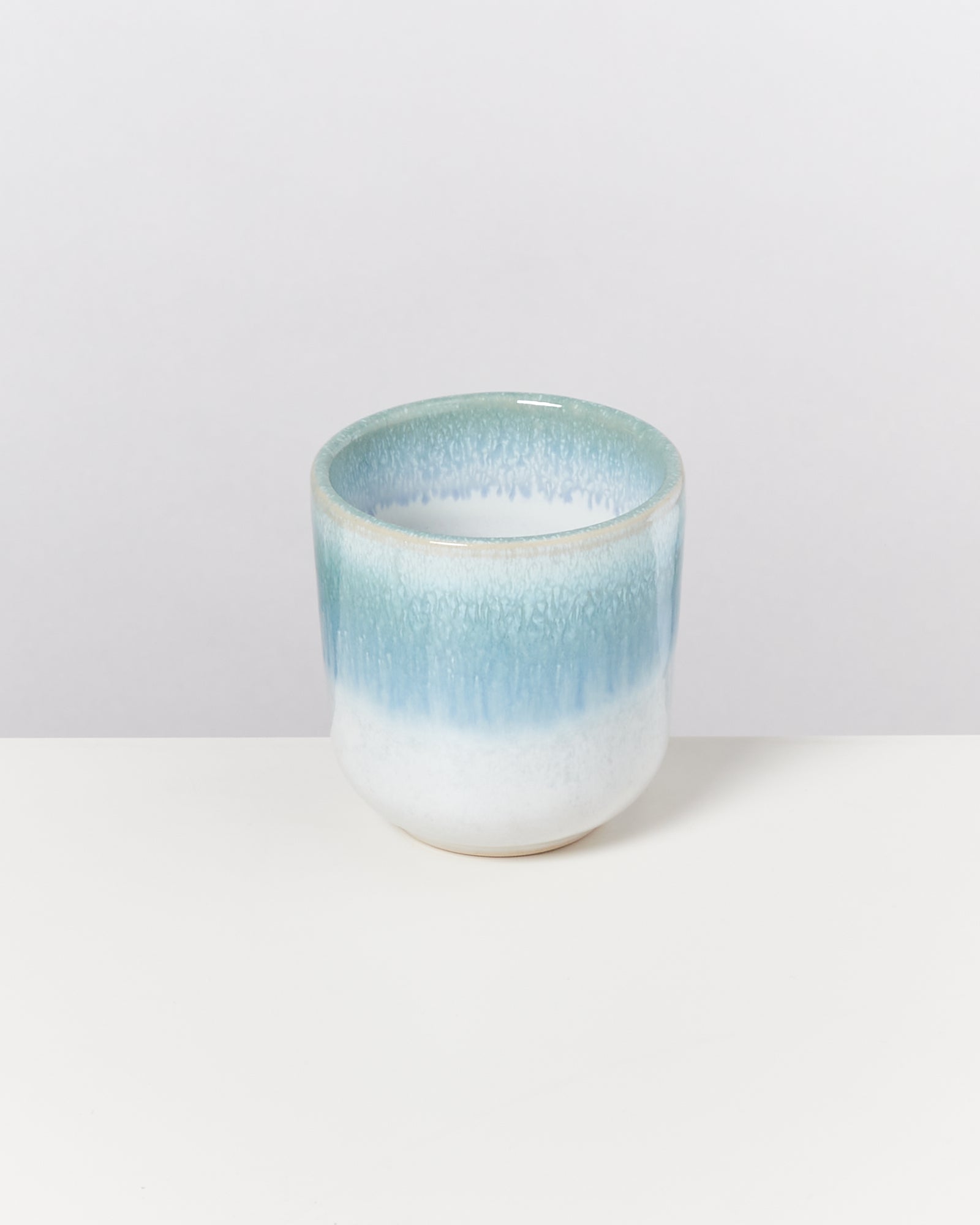 Keramikbecher mit blau-weißen Farbverläufen auf einem weißen Hintergrund.