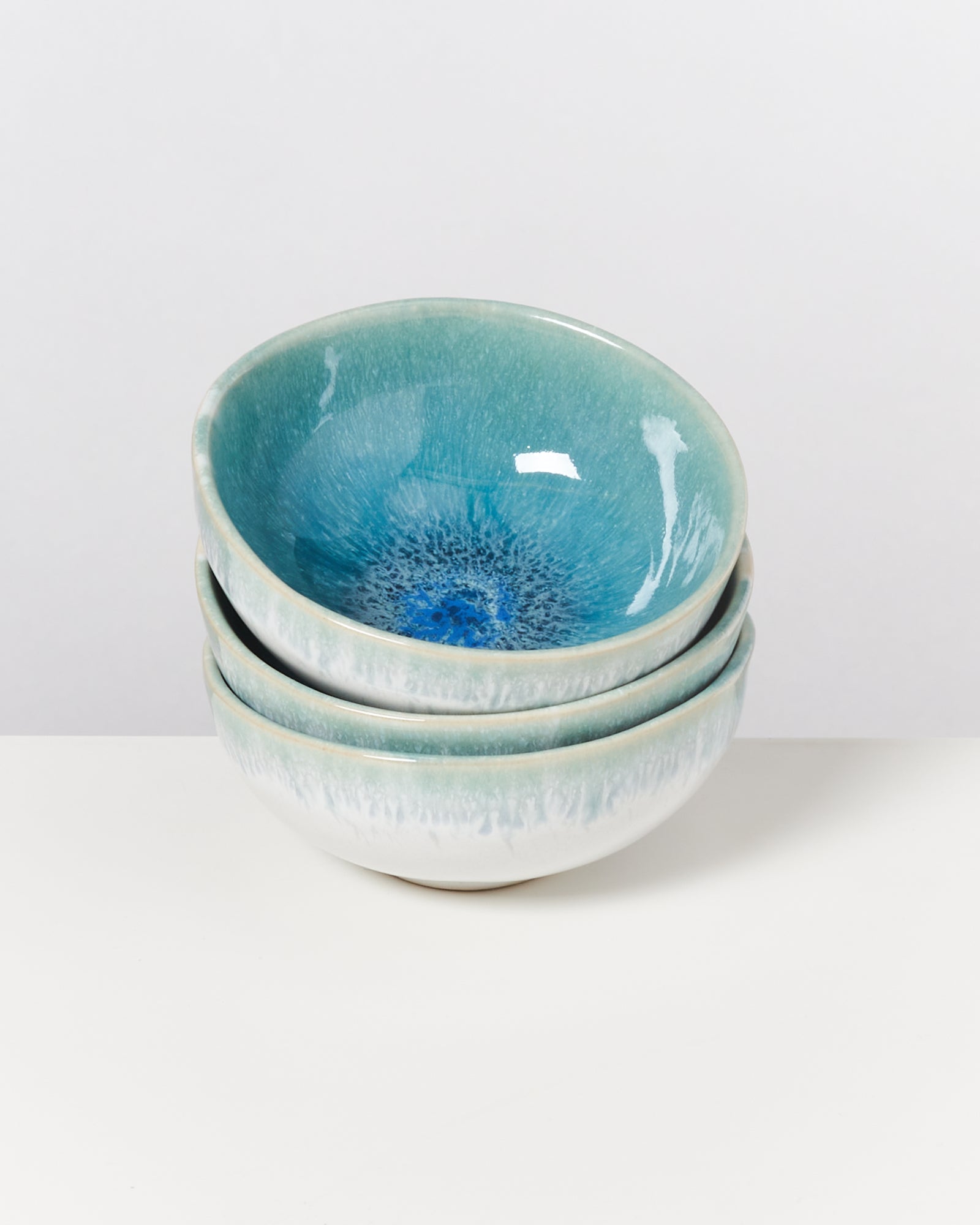 Drei gestapelte, blaue Keramikschalen mit einem dekorativen Muster im Inneren auf weißem Hintergrund.