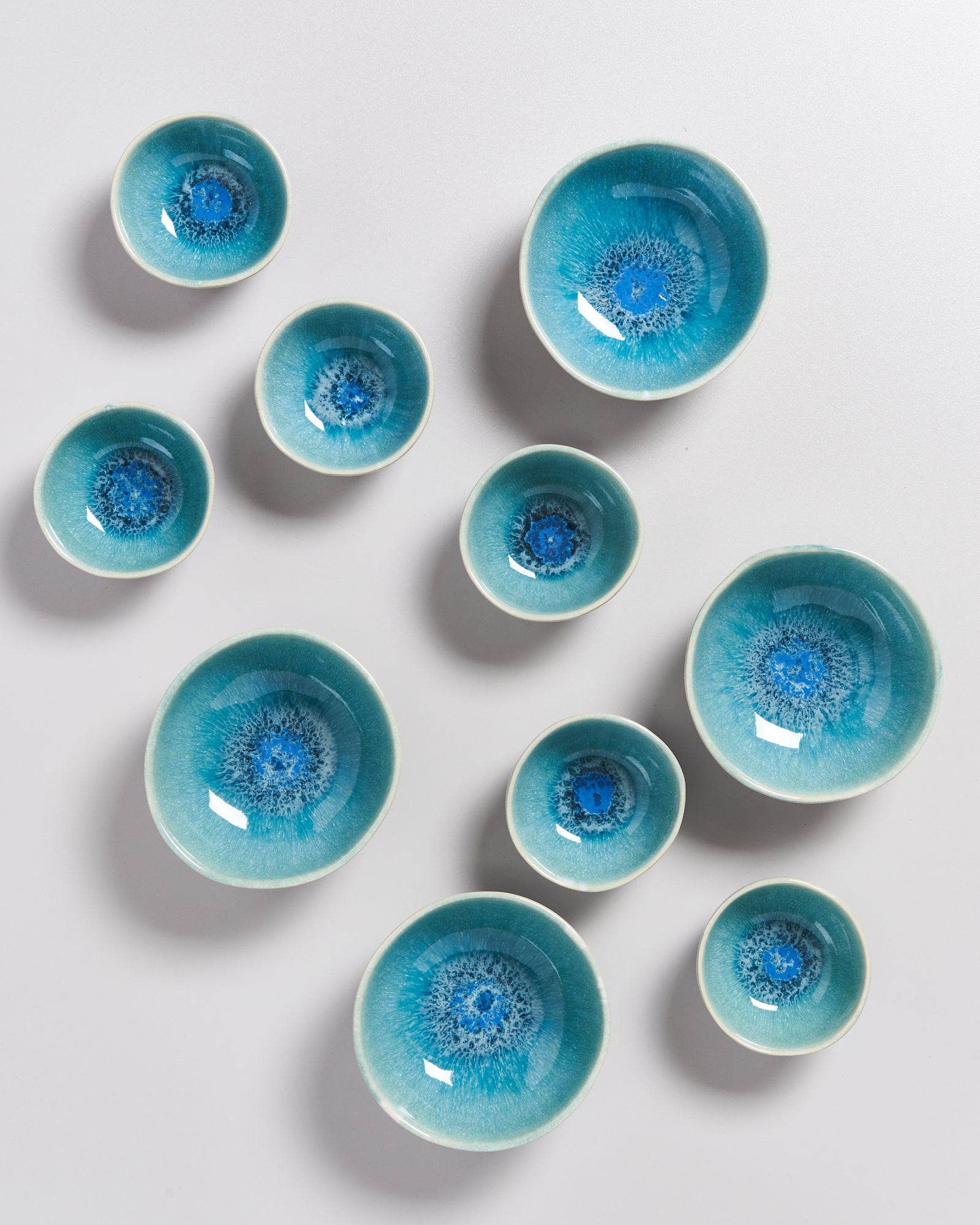 Mehrere blaue Keramikschalen mit intensivem Muster auf einer weißen Fläche verteilt.