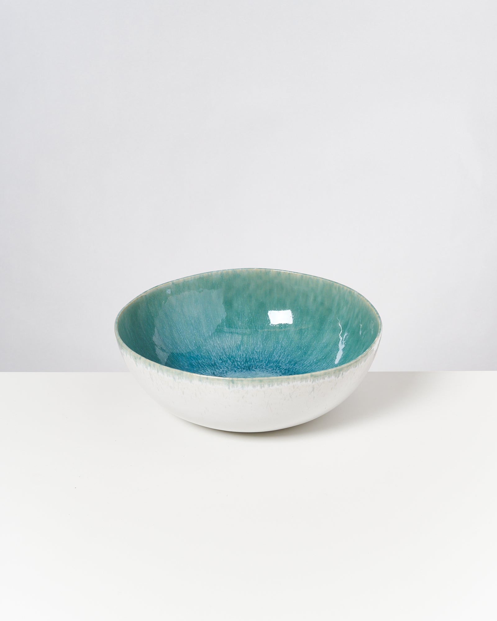 Eine runde Schale mit einem weiß-blauen Farbverlauf steht auf einem weißen Hintergrund.
