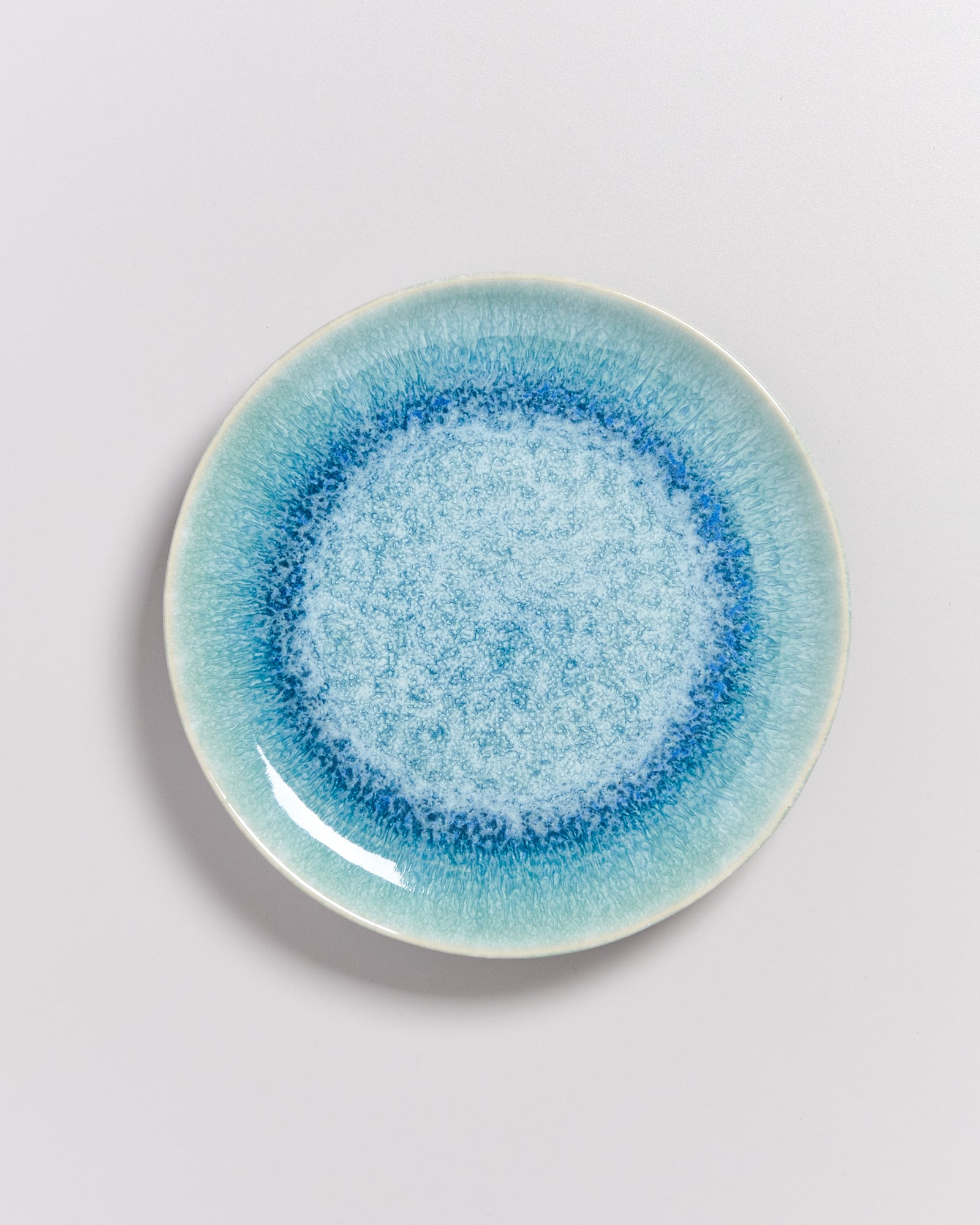 Runder Teller mit blauem und türkisem Farbverlauf auf weißem Hintergrund.