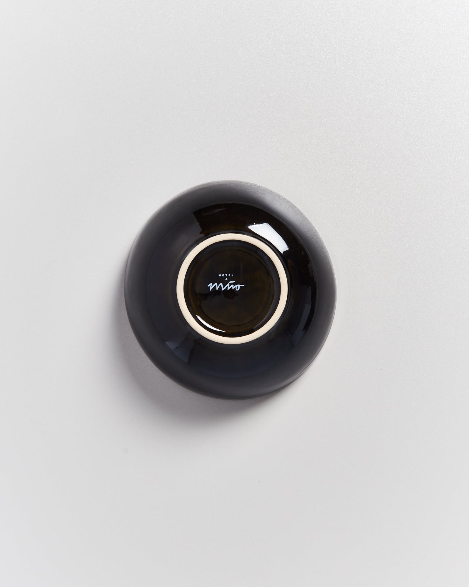 Schwarze, runde Schale mit hellem Rand und einer Aufschrift in der Mitte auf weißem Hintergrund.