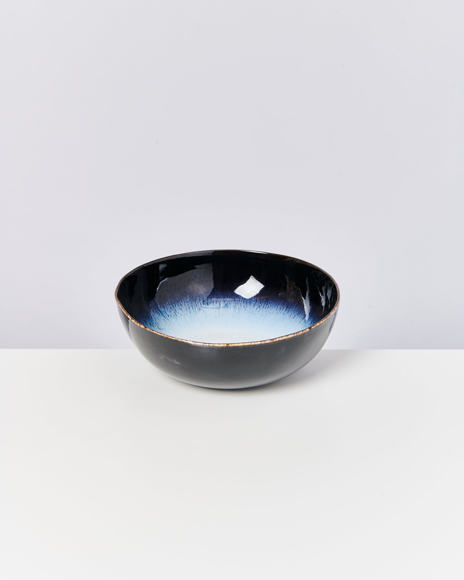 Schwarze Schüssel mit blauem Innendesign auf weißem Hintergrund.