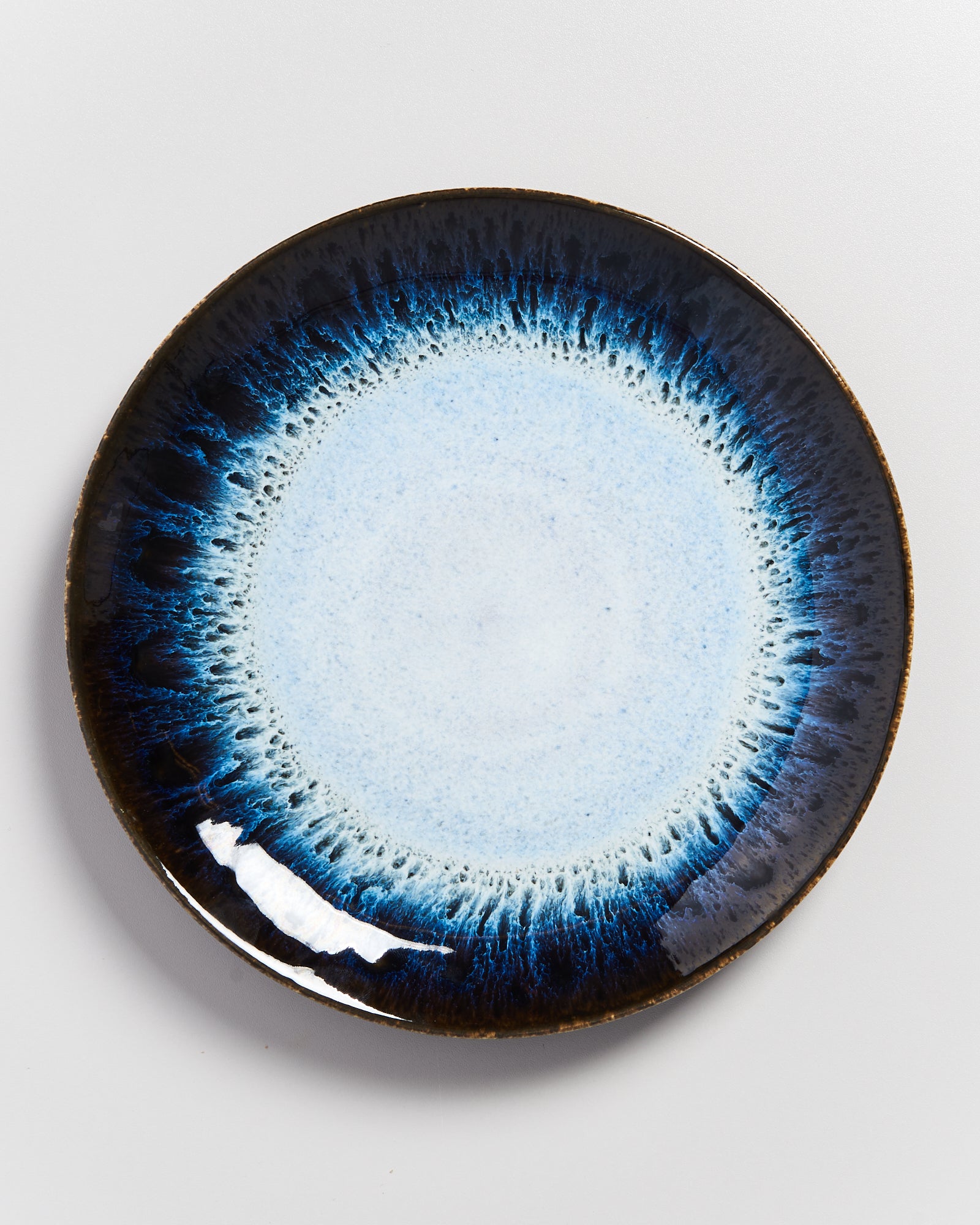 Keramikteller mit blauem Rand und hellem Zentrum auf weißem Hintergrund.
