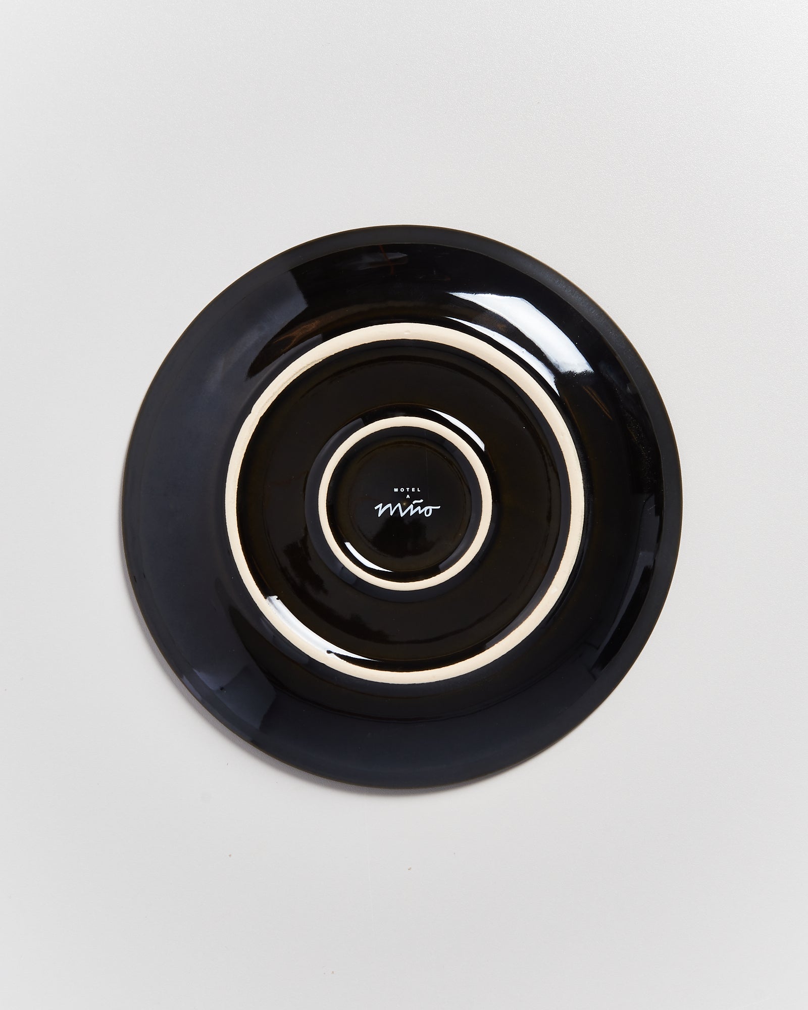 Schwarzer Teller mit weißem Rand und dem Logo vom „Hotel Miro“ in der Mitte auf hellem Hintergrund.