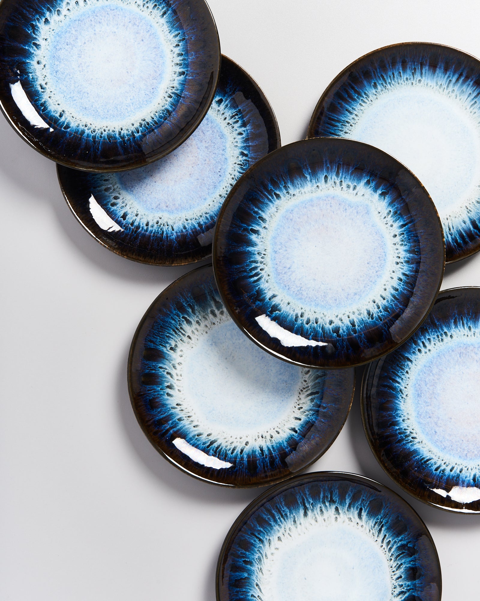 Ein Arrangement aus sieben dekorativen Tellern mit blauem und weißem Muster auf einem hellen Hintergrund.