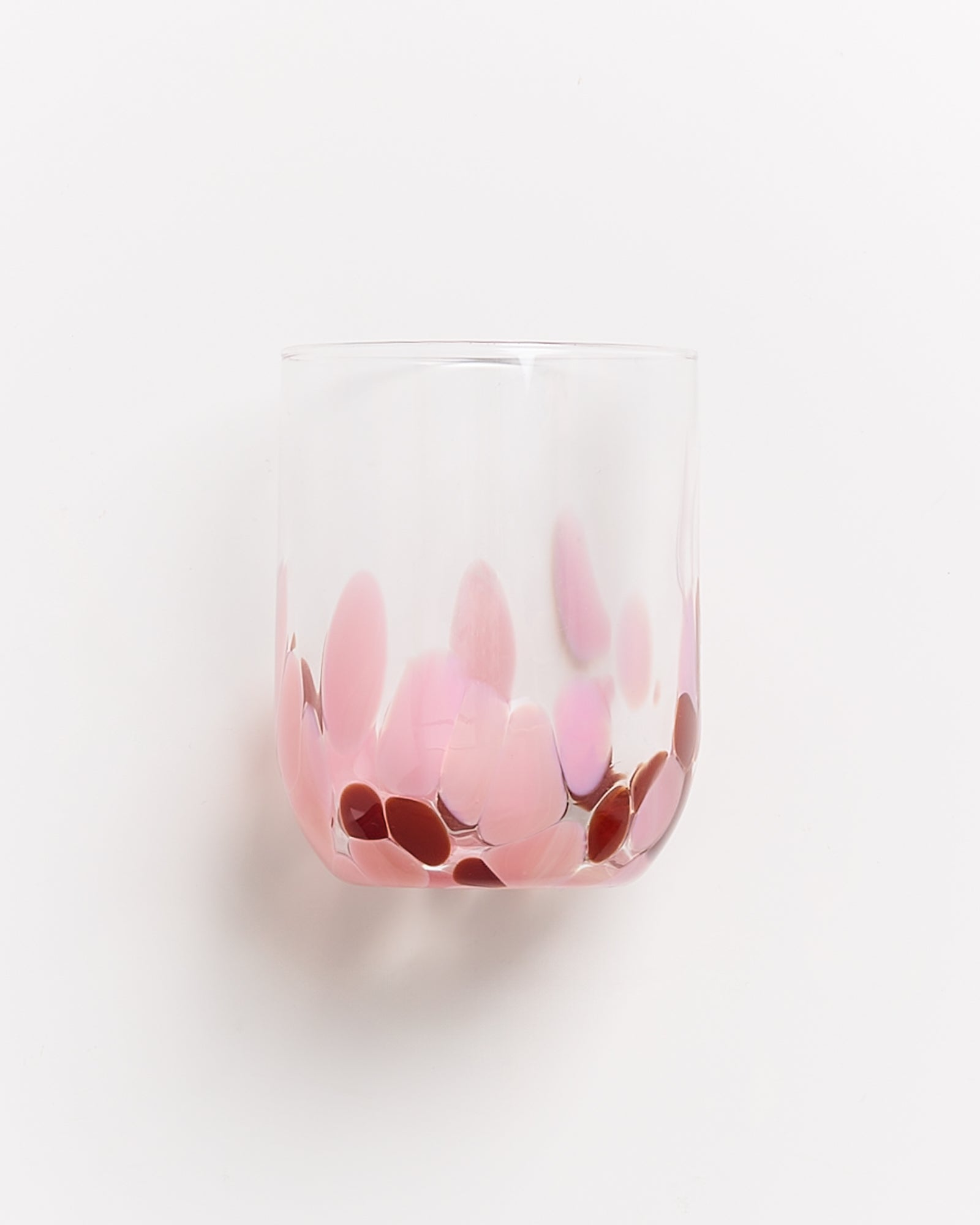 Ein transparentes Glas mit rosafarbenen und roten Tupfen auf weißem Hintergrund.