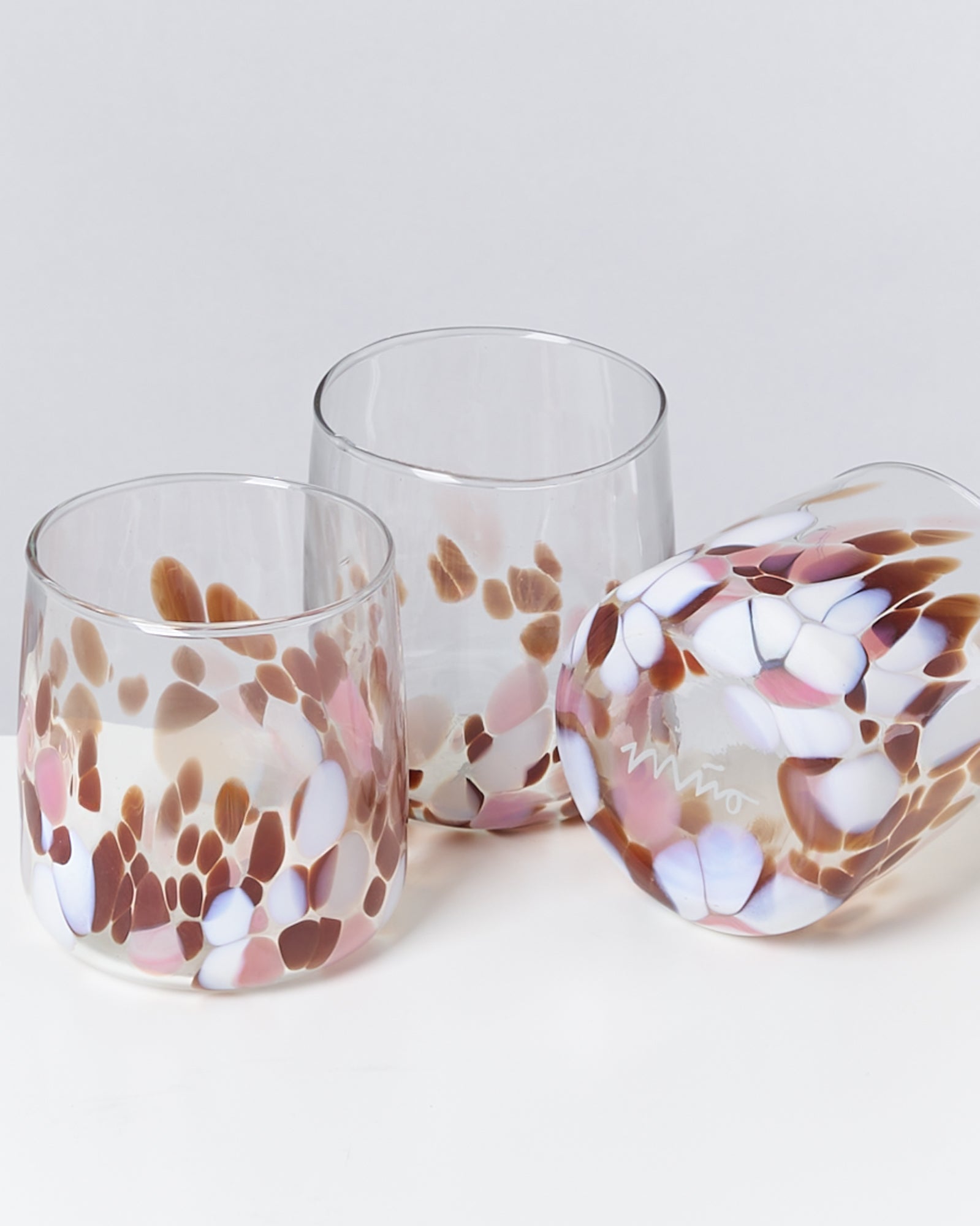 Drei Gläser mit bunten, marmorierten Mustern in Rosa, Weiß und Braun auf hellem Hintergrund.