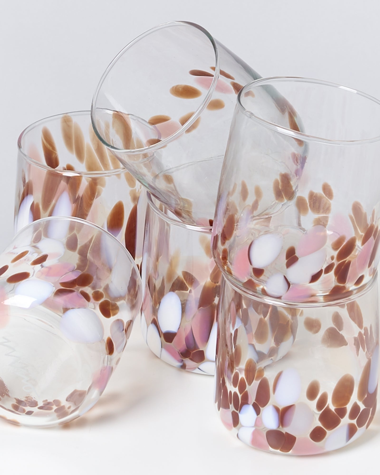 Sechs Gläser mit braunen, weißen und rosa Flecken sind künstlerisch gestapelt.