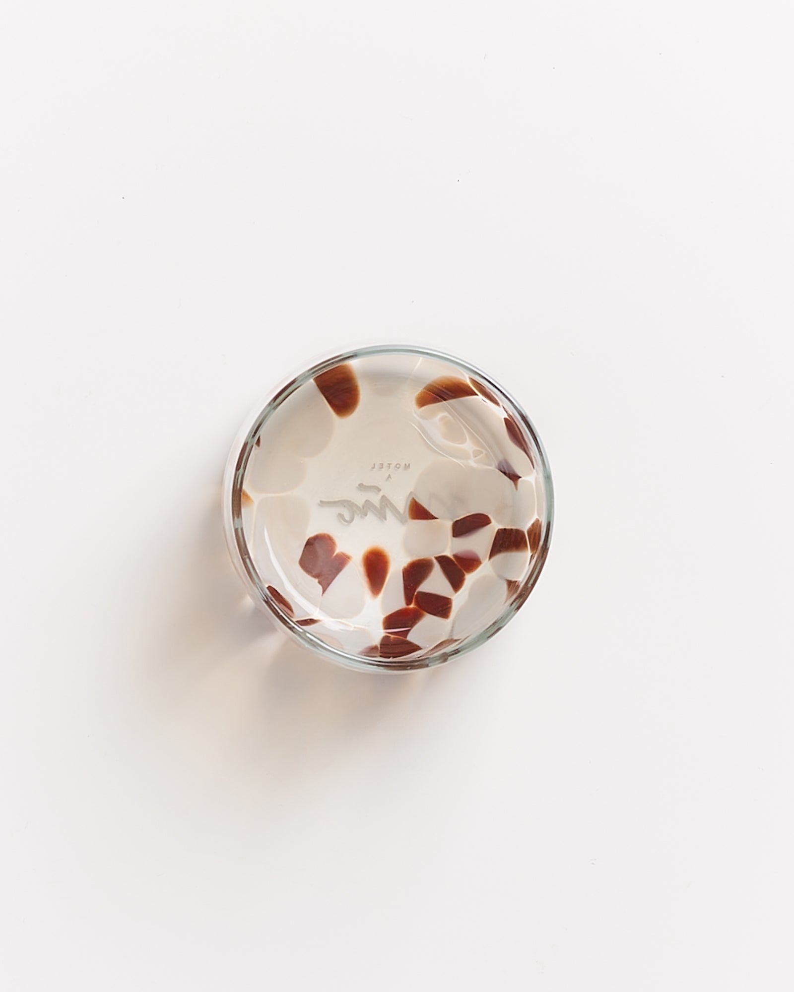 Runde Glasschale mit braunen und weißen Mustern auf weißem Hintergrund.