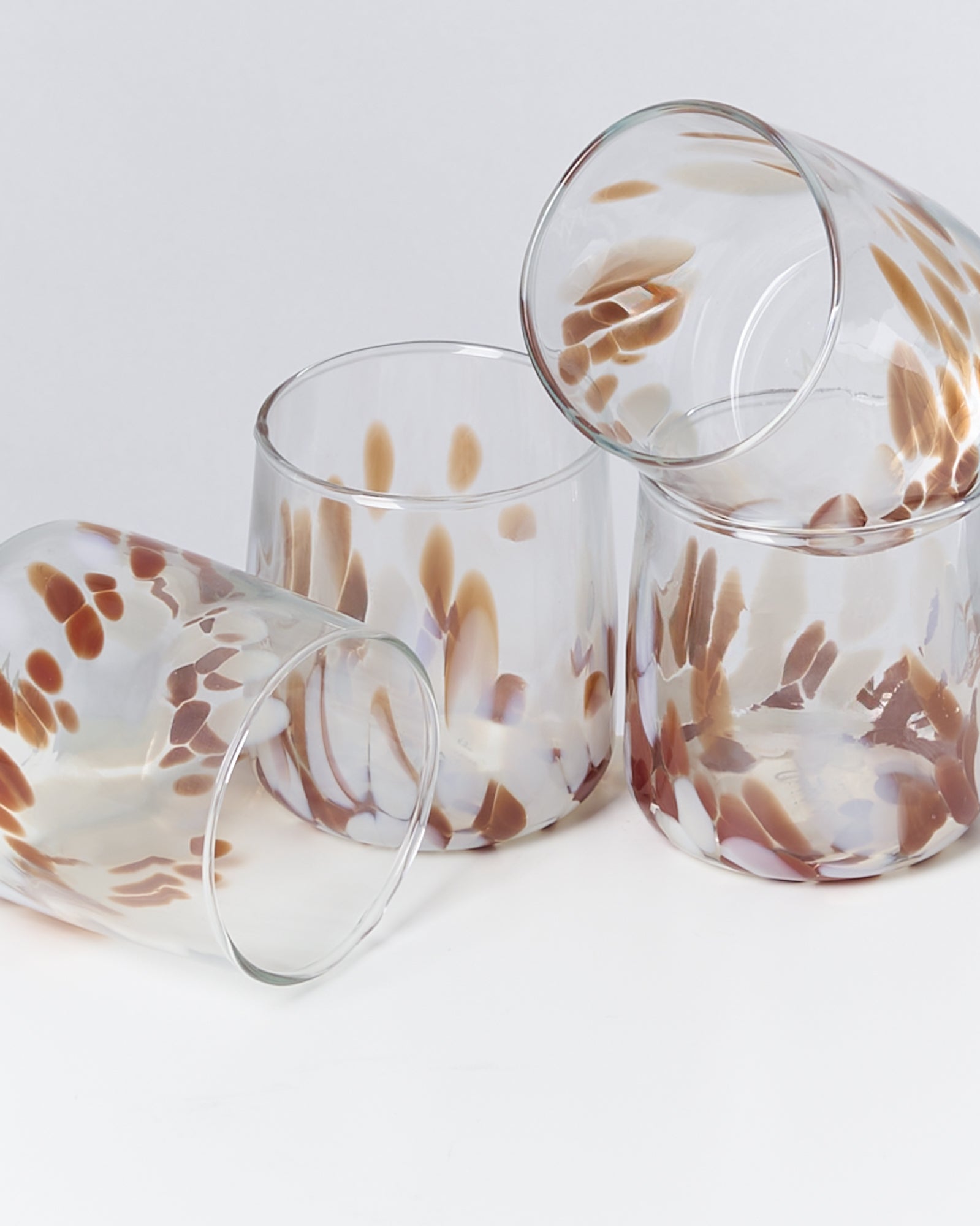 Vier Gläser mit braunen und weißen Mustern auf weißem Hintergrund.