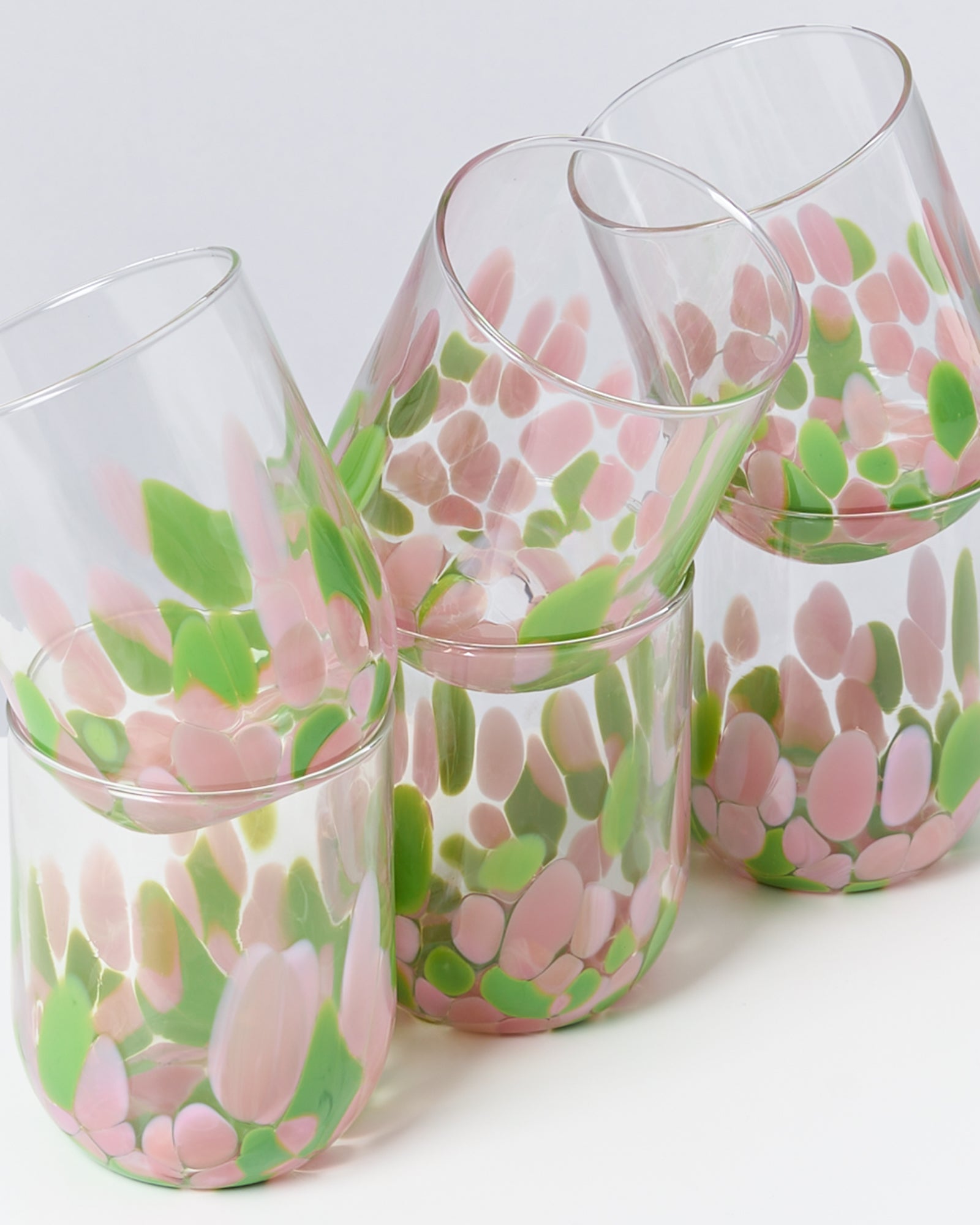 Fünf dekorative Gläser mit rosa und grünen Farbmuster auf weißem Hintergrund.