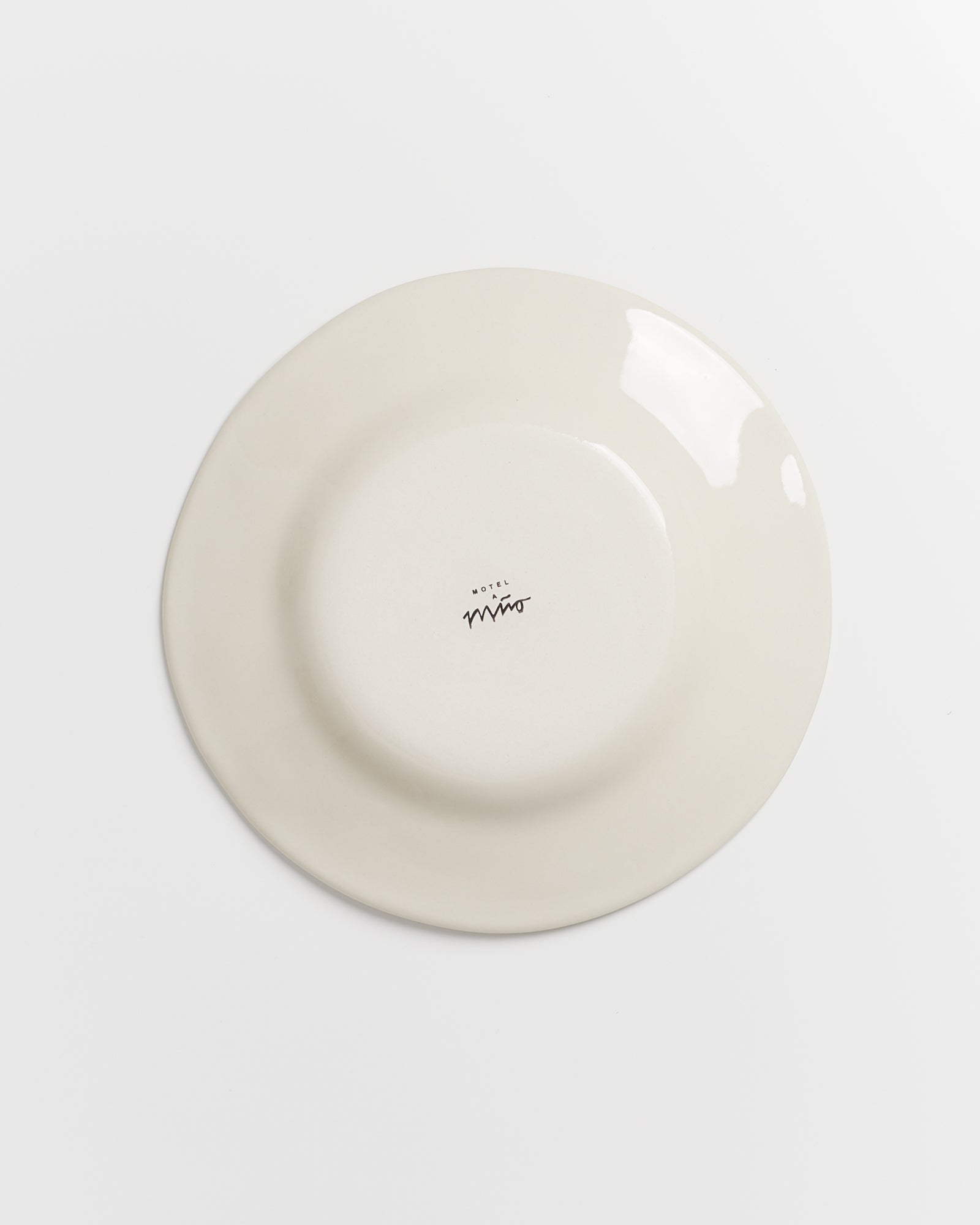 Eine umgedrehte, cremefarbene Platte mit der Aufschrift „Hotel Miro“ in der Mitte, auf weißem Hintergrund.