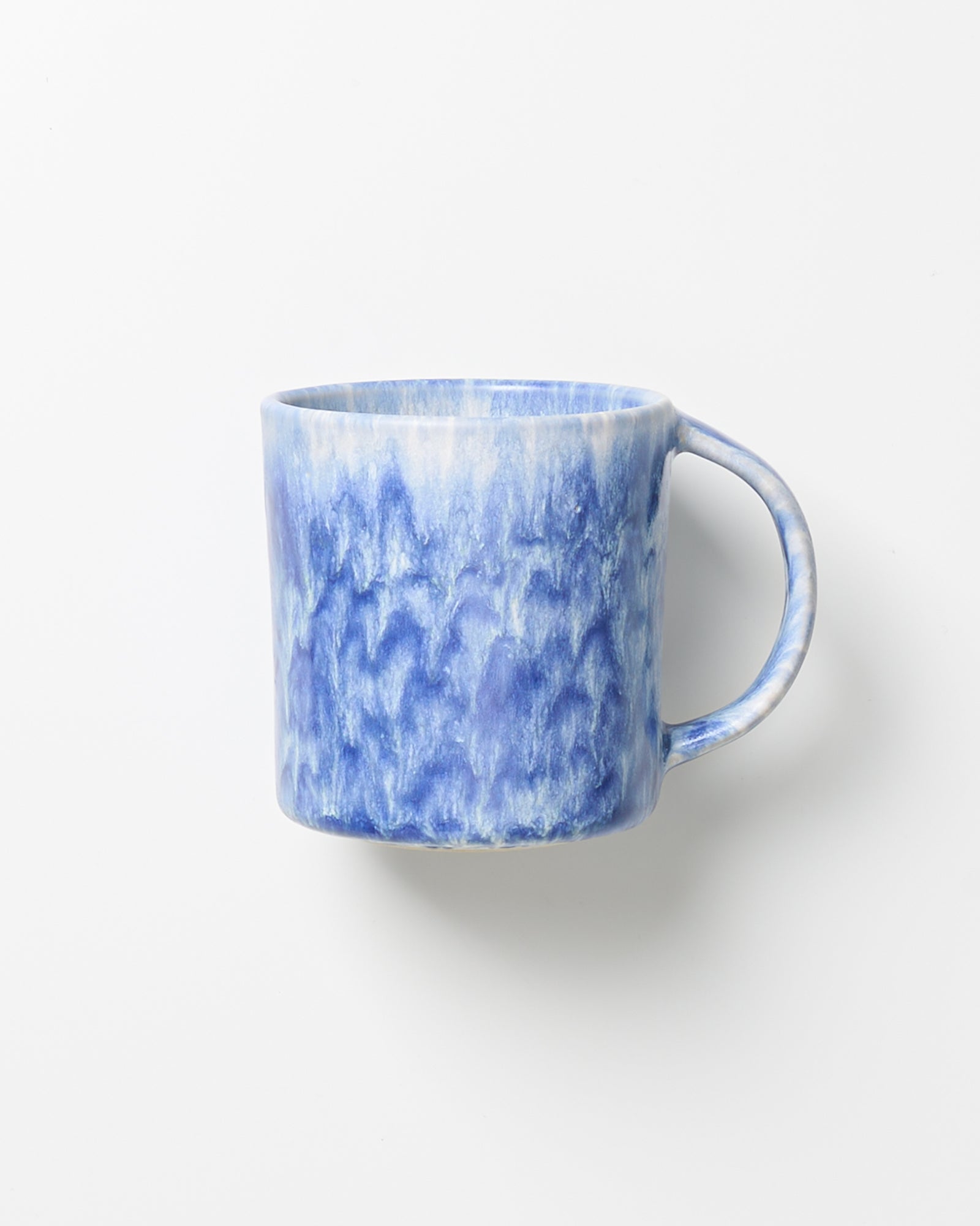 Blaue Keramiktasse mit marmoriertem Muster auf weißem Hintergrund.