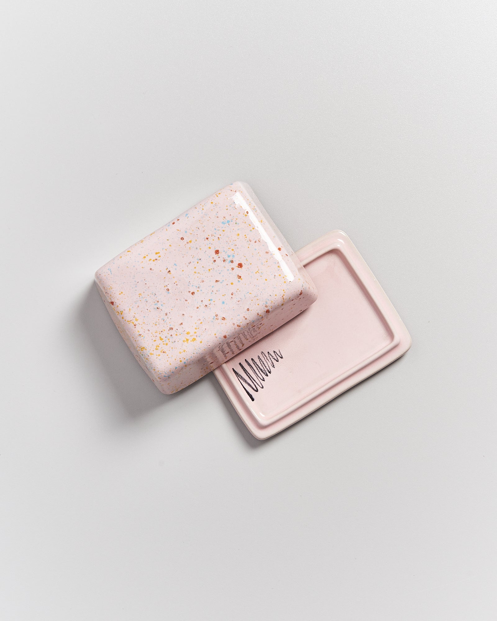 Rosa, gesprenkelte Seifenschale auf hellem Hintergrund, teilweise geöffnet mit einem Schriftzug auf der Innenseite.