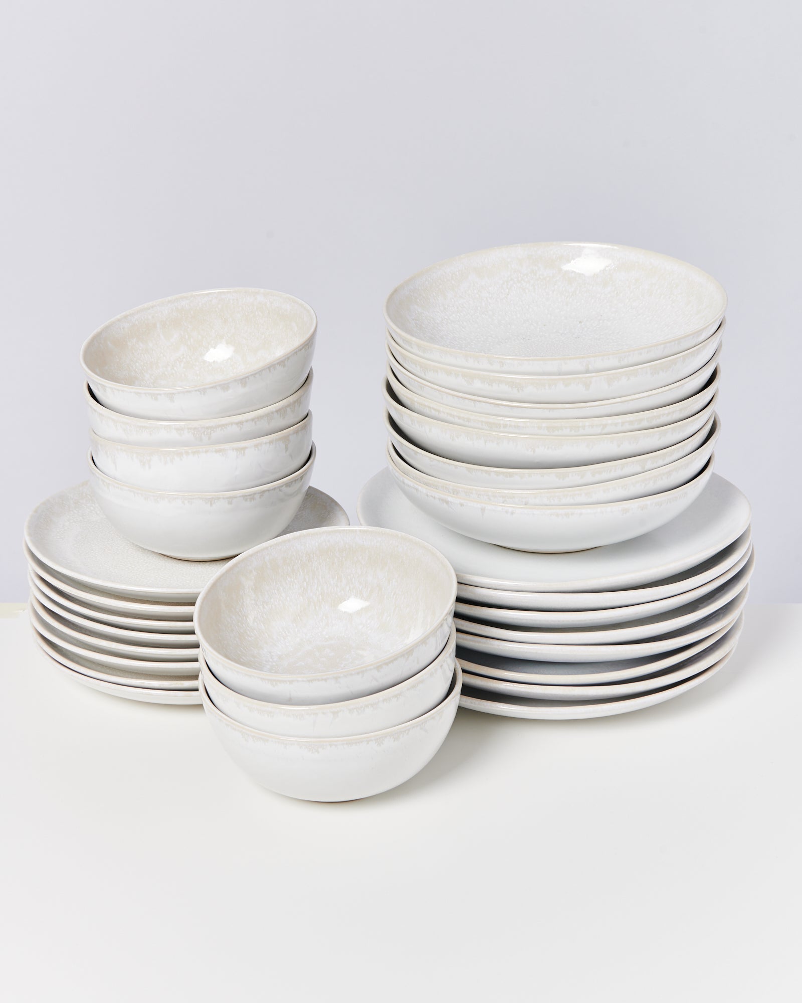 Stapel weißer Schalen und Teller auf einem Tisch vor einem hellen Hintergrund.