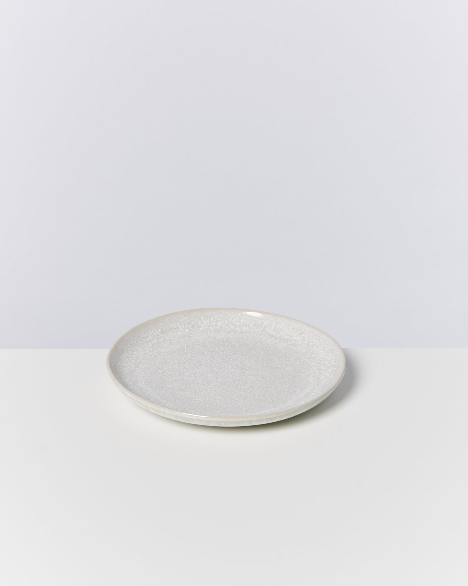 Ein einfacher, beiger Teller mit Textur auf einem weißen Hintergrund.