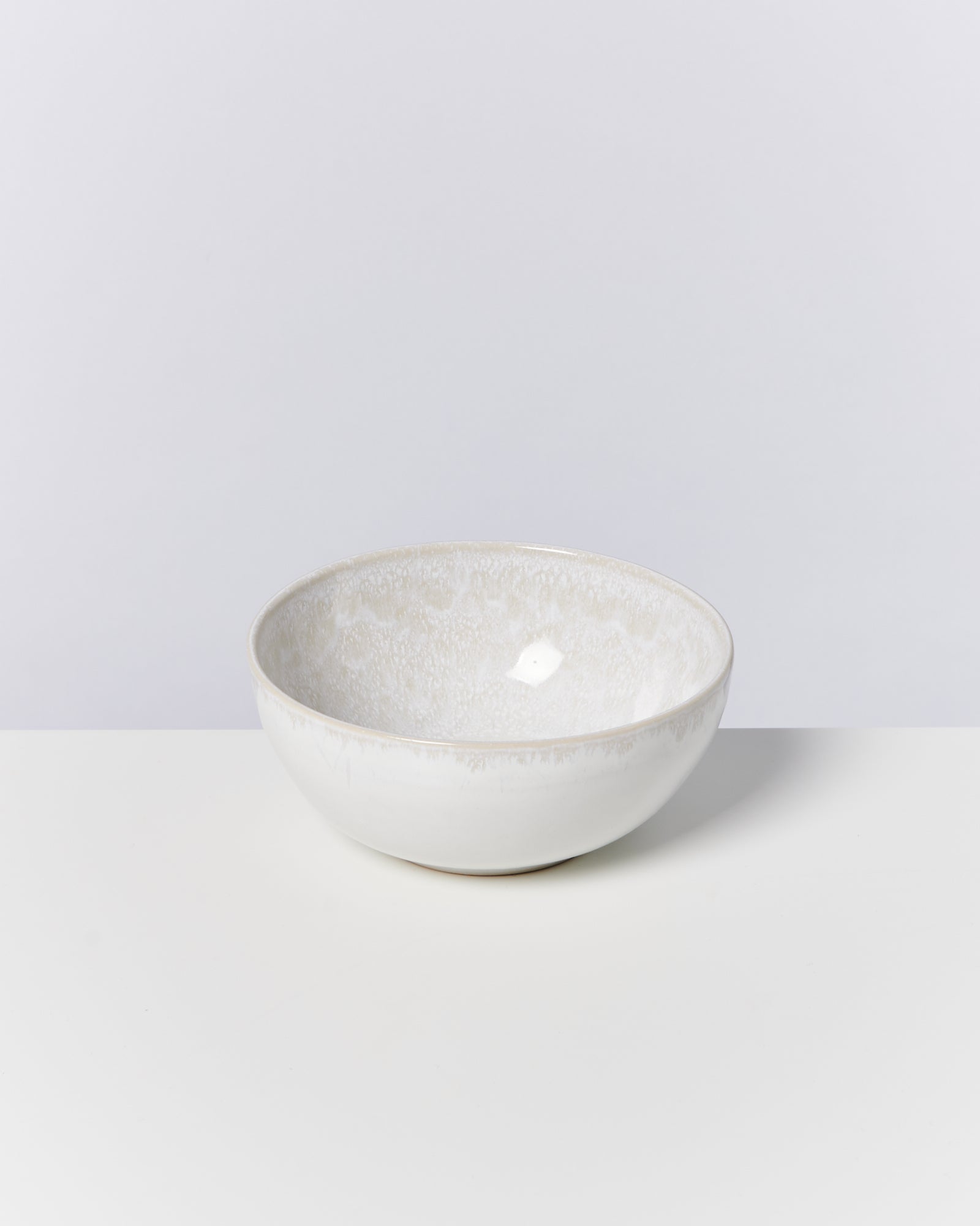 Weiße Keramikschüssel auf einem weißen Untergrund vor neutralem Hintergrund.